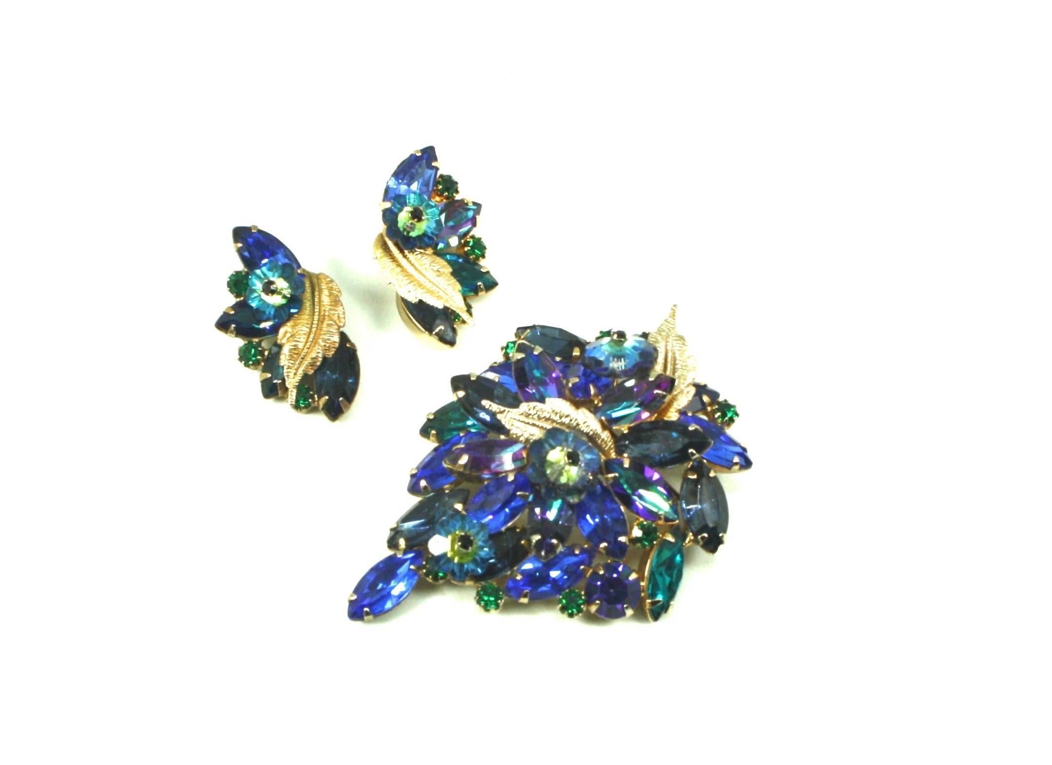 Exquisite floral themed brooch and clip earrings suite by American fashion model turned jewellery maker Alice Caviness. Glass stones are claw-set in hues of blue, green and purple. Measurements below are for the brooch. Measurements for the clip