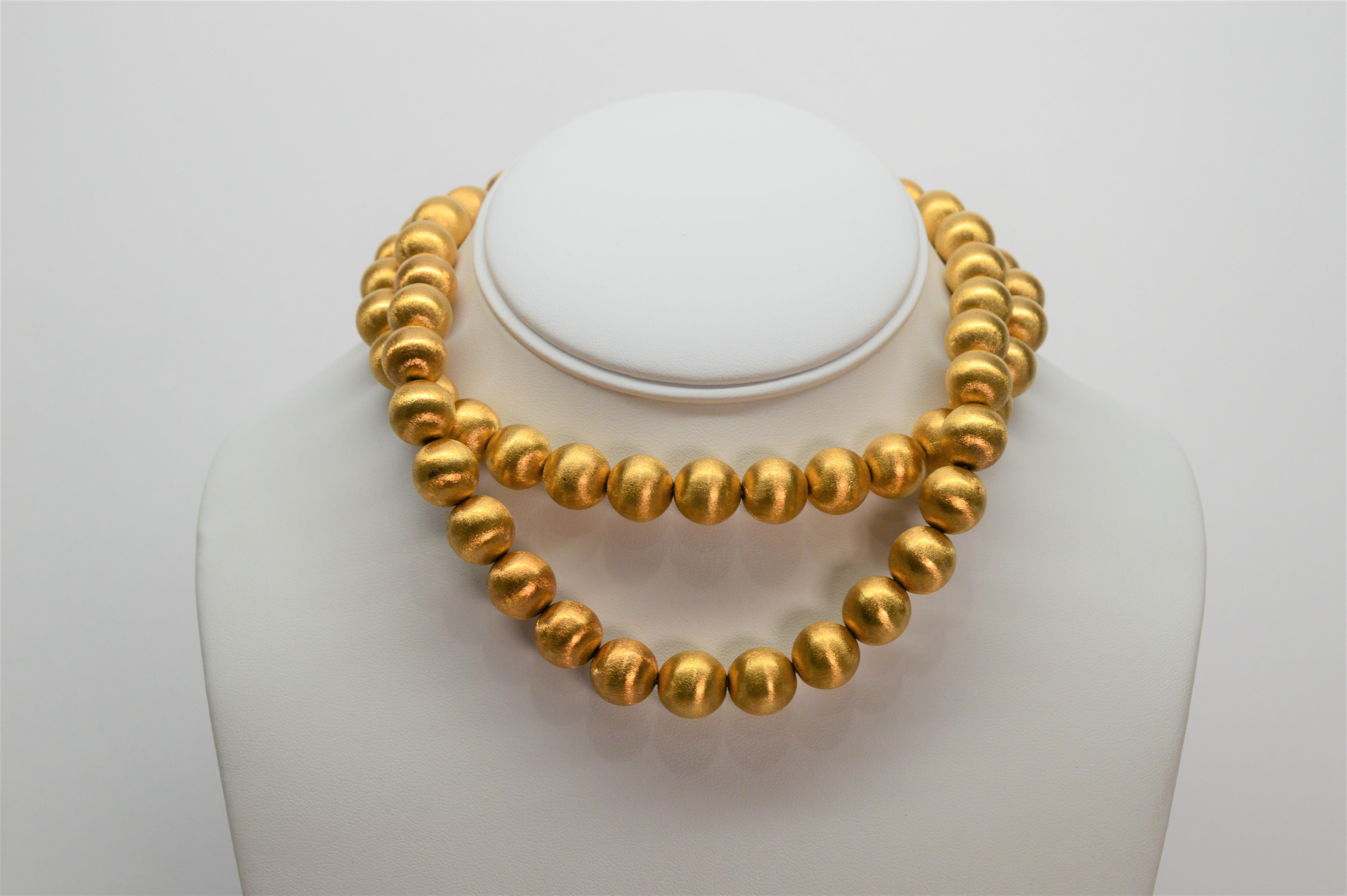 Circa 1950's, extremely fine and a rare find in mint condition, this glamorous necklace and earring set is a showstopper. Sixty-four 11.88mm brushed eighteen karat (18K) gold beads create this glorious 28 inch strand. Complimented by 15 mm matching