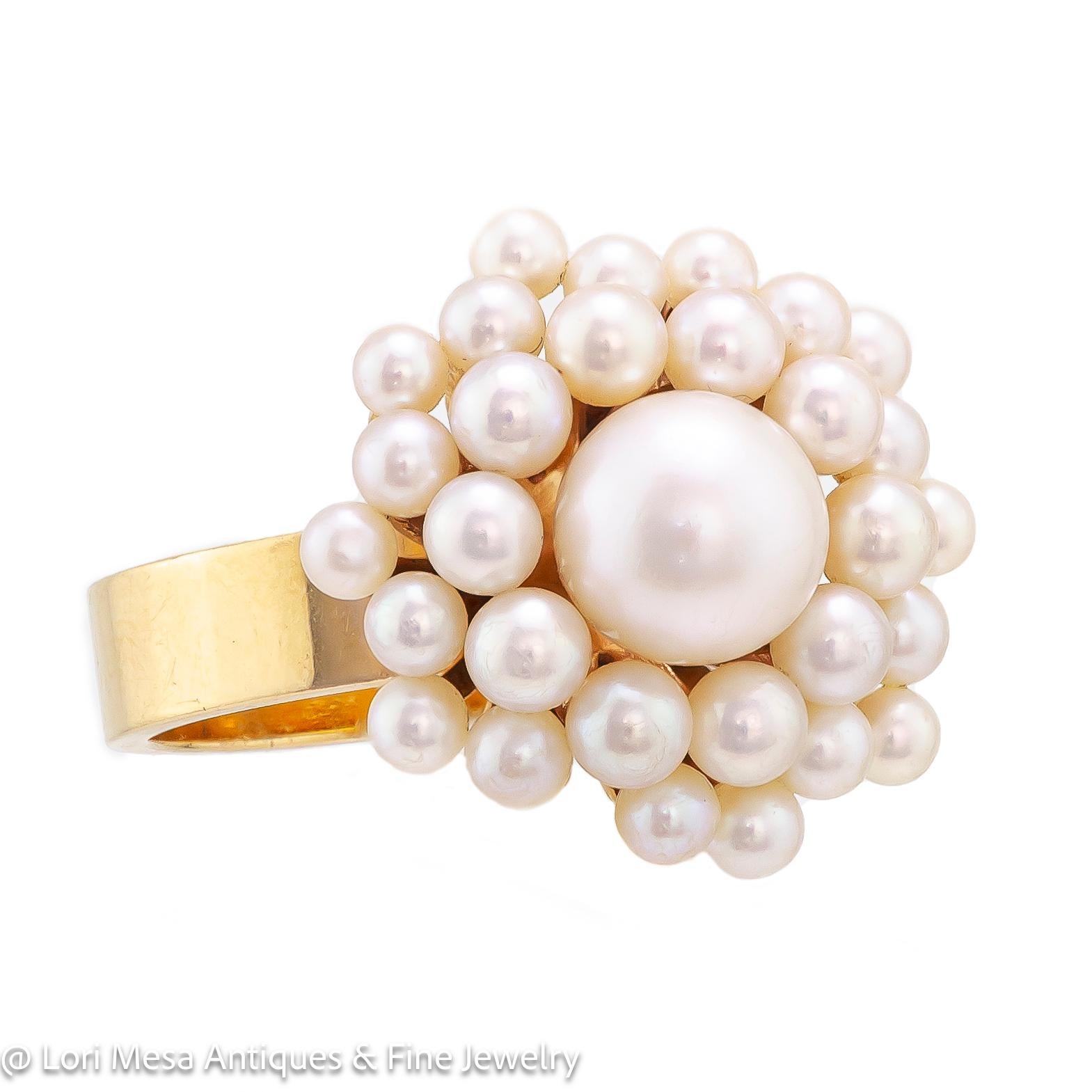 Circa 1960 cultured pearl and yellow gold cluster ring set with one (1) round cultured pearl measuring approximately 7.5mm surrounded by numerous round cultured pearls measuring approximately 3 or 4 mm each all set in a 14kt yellow gold mount of