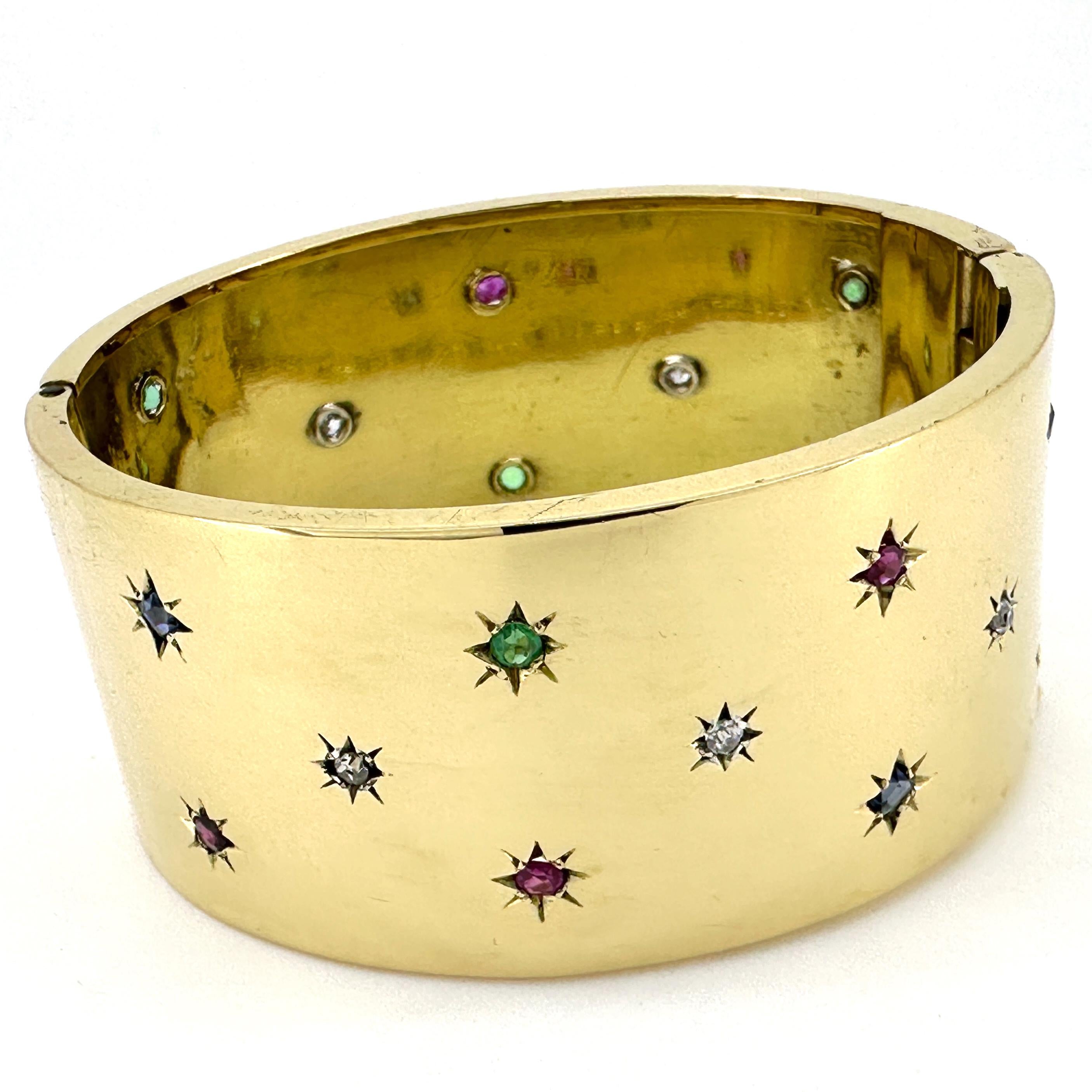 This sturdy bangle, custom made in the 1960's, is solid gold and built to last.  It features nineteen small gemstones -- jewelry's big four: diamonds, emeralds, sapphires and rubies -- each set in a star-cut bezel.  

The oval-shaped bangle is