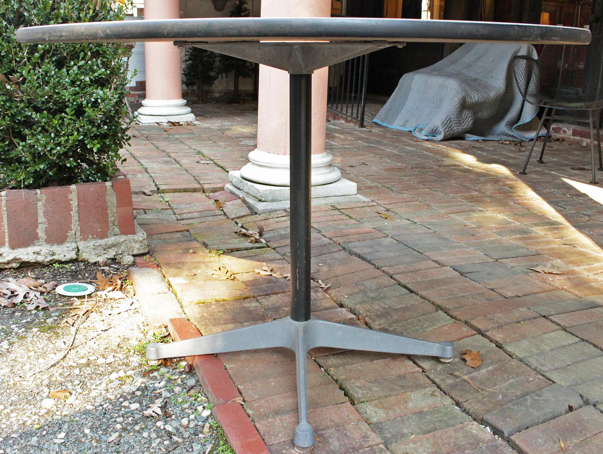 A circular dining or work table, made by Herman Miller, c.1960s-70s. Designed by Charles Eames. Mid century modern Aluminum Group, 4 prong chrome base with white laminate top with black edge & with black shaft (minor scratches). Label: 
