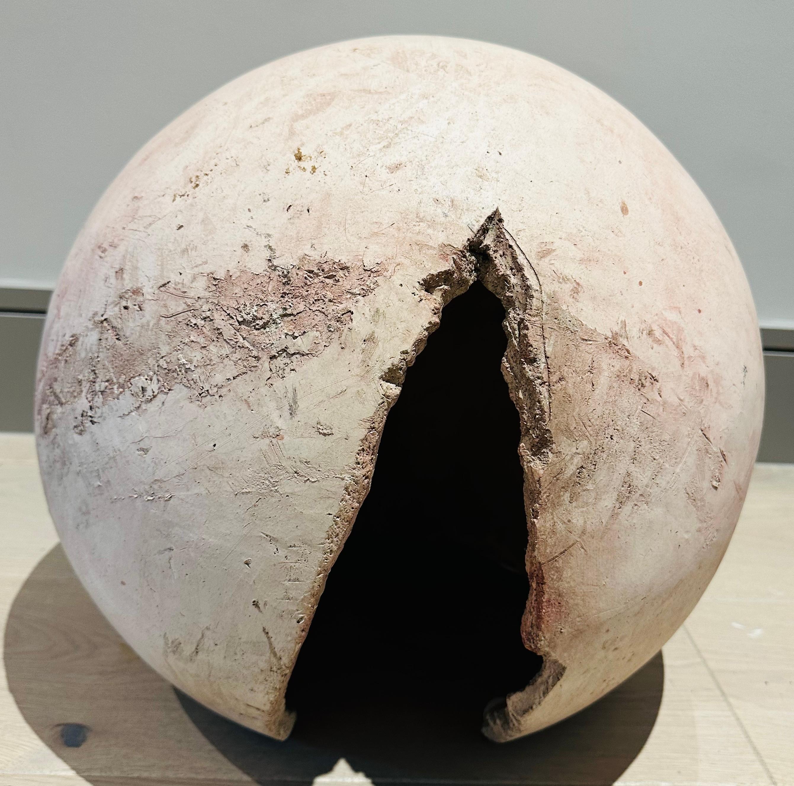 1960s French abstract terracotta futuristic sculpture in the form of a cracked circular egg.  The sculpture has an unglazed chalky surface which is smooth with an unfinished feature rough line running from the top of the crack .  The structure is