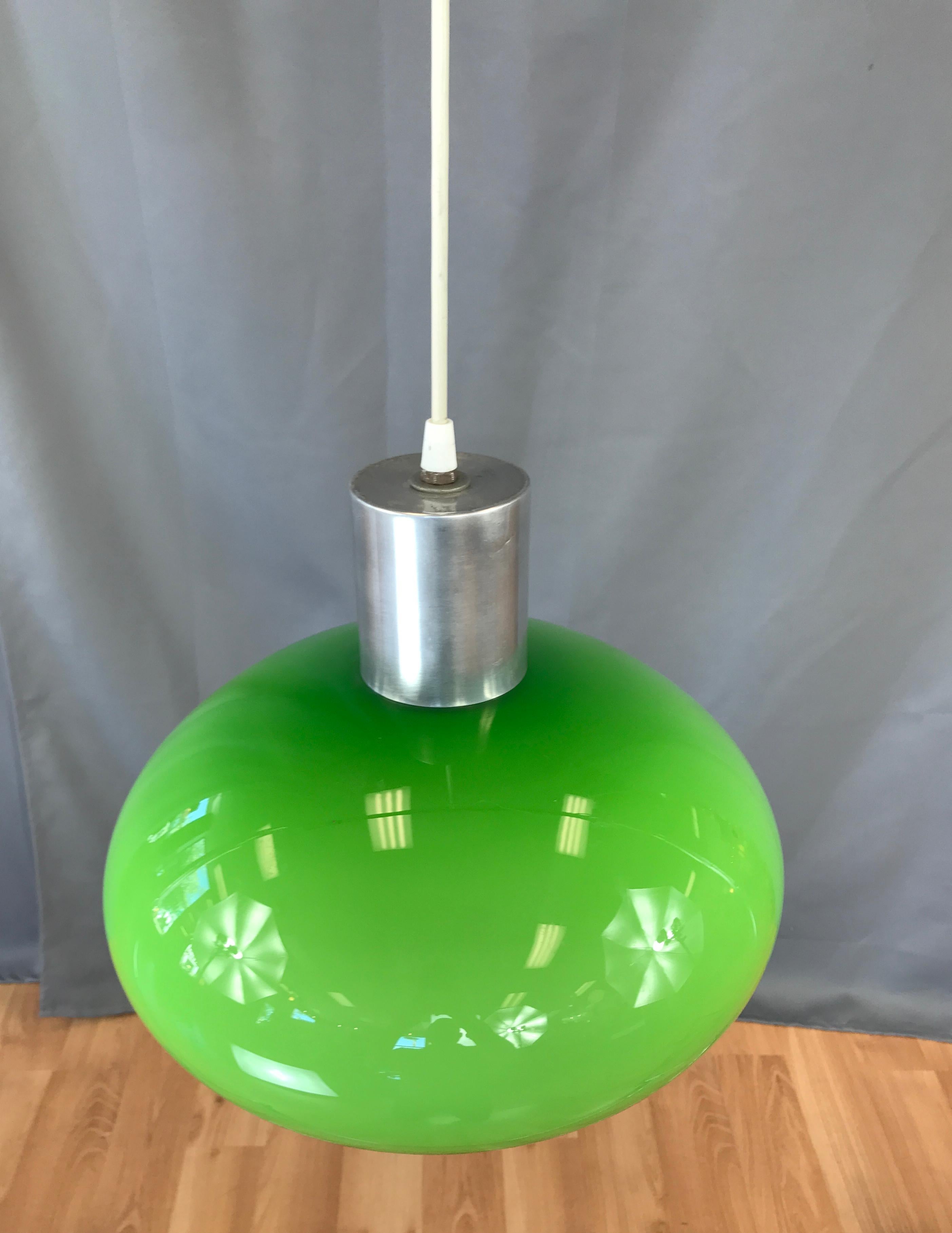 Green cased glass pendant light, circa 1960s.
Shade is green and a white inside, when lit gives a nice glow (last 2 photos) glass shade is attached to a metal cylinder from which the white cord comes out. The long cord has a two prong plug, but