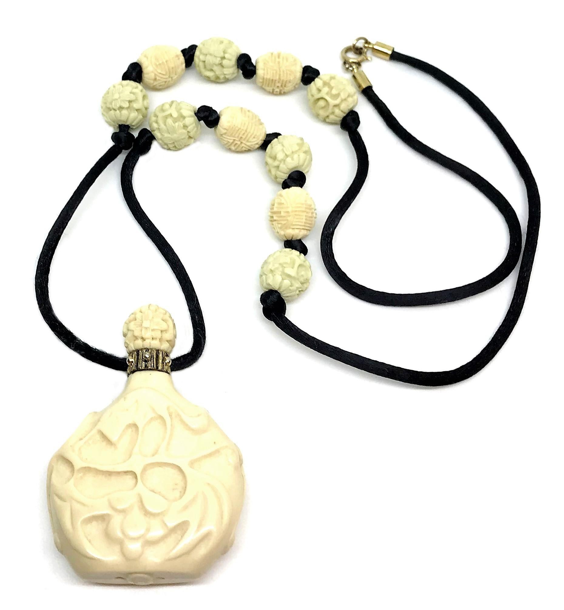 Circa 1960s Hattie Carnegie black cord necklace with a molded faux-snuff bottle pendant and embellished with molded Asian character and floral beads in pale green and ivory colors.  The necklace measures 26