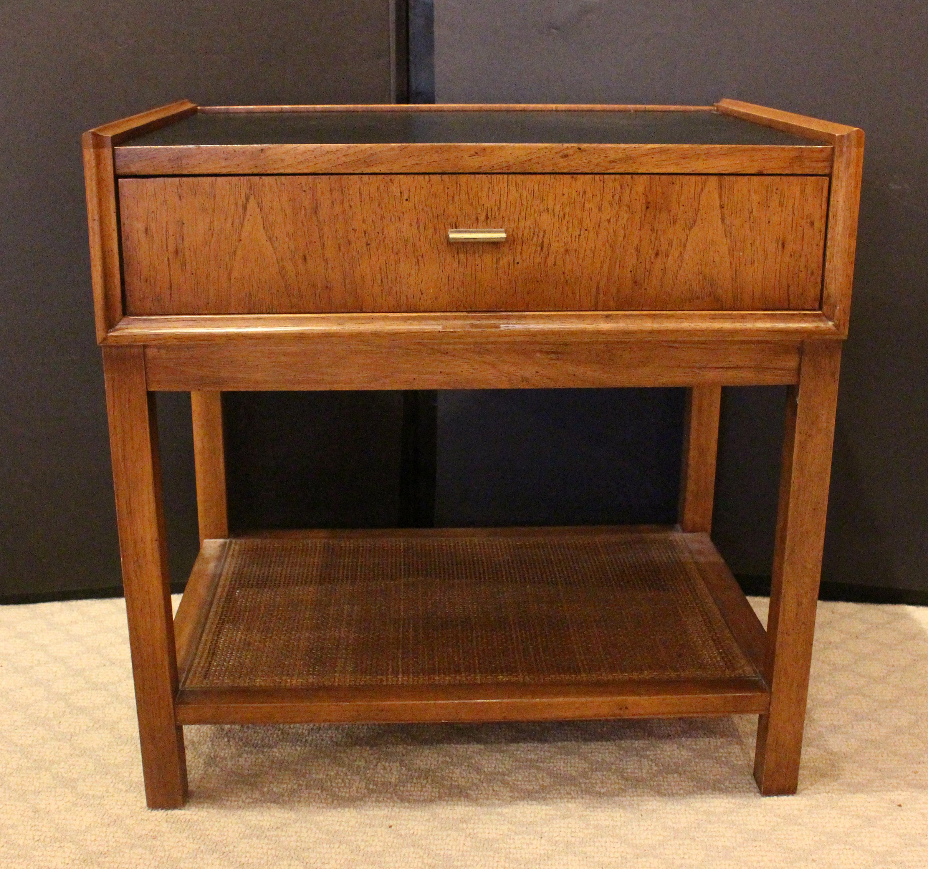 Mid Century Modern night stand made by Founders, c.1960s. Rarely found design by Jack Cartwright. Solid pecan, brass & cane shelf. Top inset with grained leather. Not signed, but identical to other branded pieces.
22
