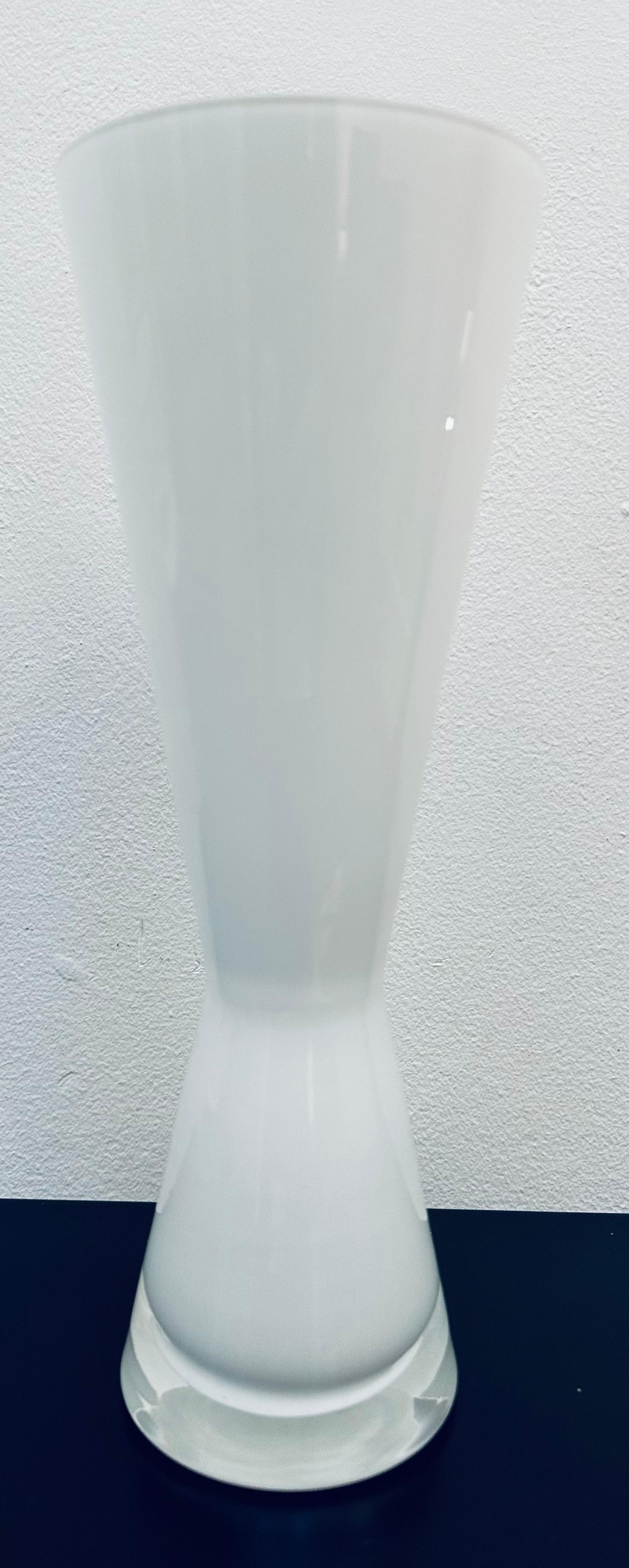 Circa 1960s milk and clear encased glass vase in the style of Holmegaard . The vase is constructed of two layers of glass: a milk-coloured inner-layer and a clear outer layer with a feature 1 cm clear glass base. The two layers of glass are fused