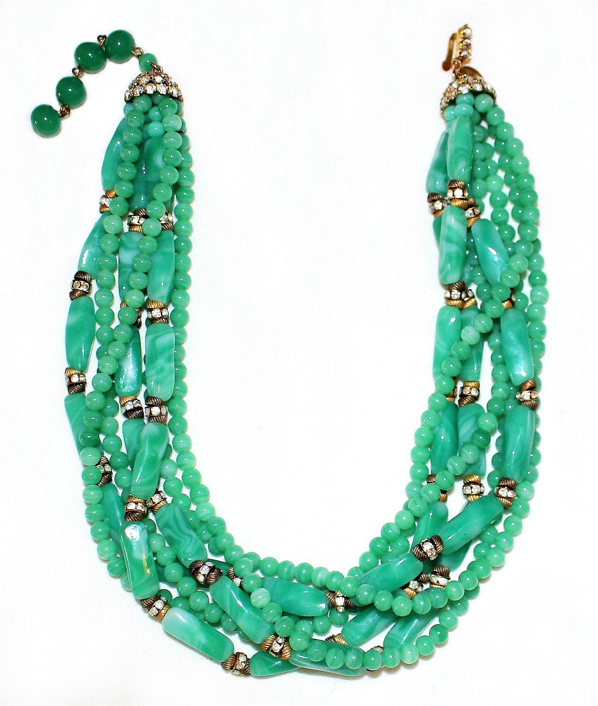 Circa 1960s William deLillo multi-strand, green glass bead necklace embellished with clear rhinestone roundels and gold tone spacers. All the strands are held together at each end with prong-set rhinestone caps. The length of the necklace ranges
