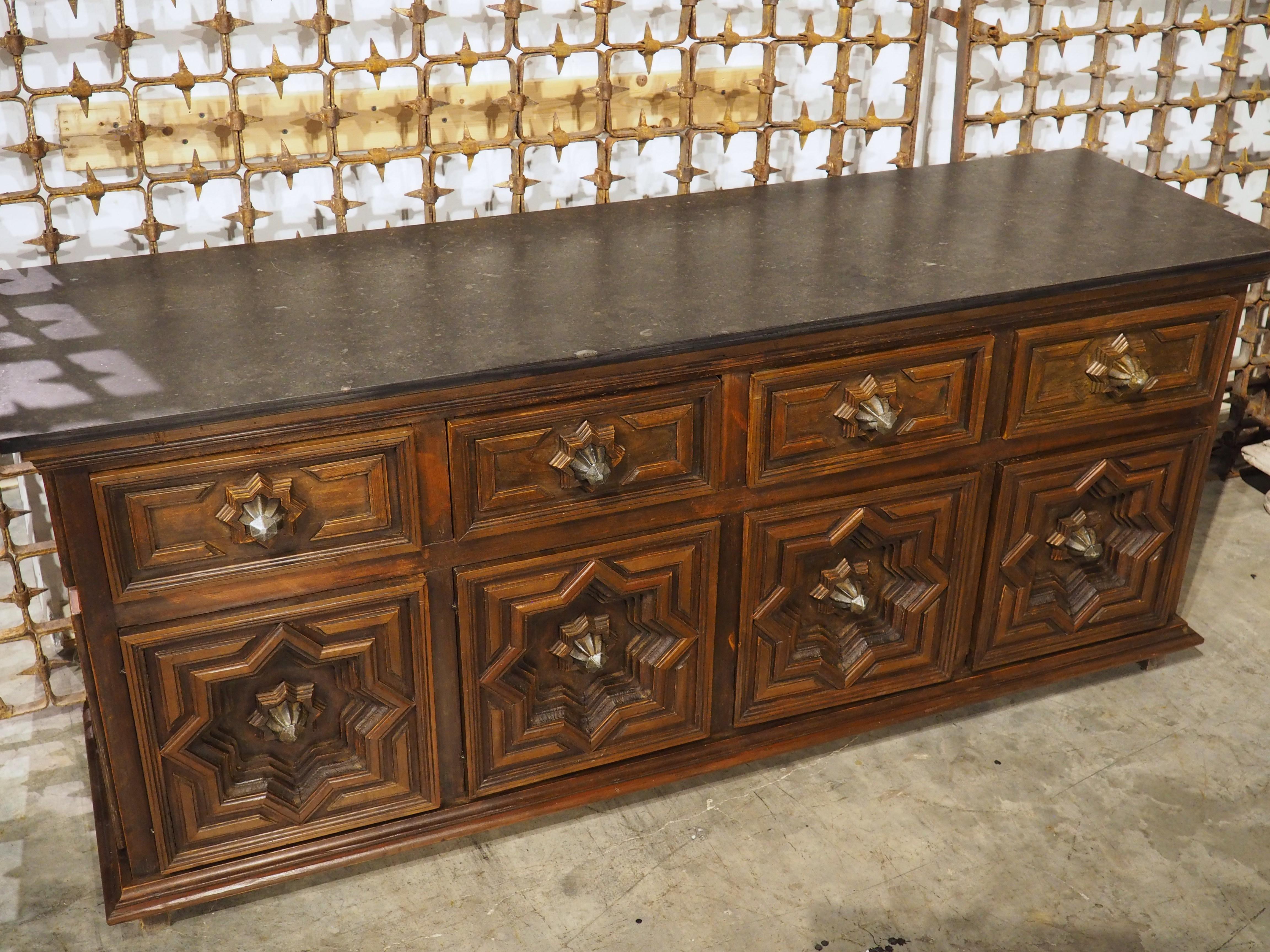 Ulteriori informazioni in arrivo...

Un'affascinante enfilade a quattro porte, risalente al 1970 circa.  Il buffet in legno altamente intagliato presenta profondi pannelli geometrici sotto un piano in pietra nera con alcune inclusioni fossili