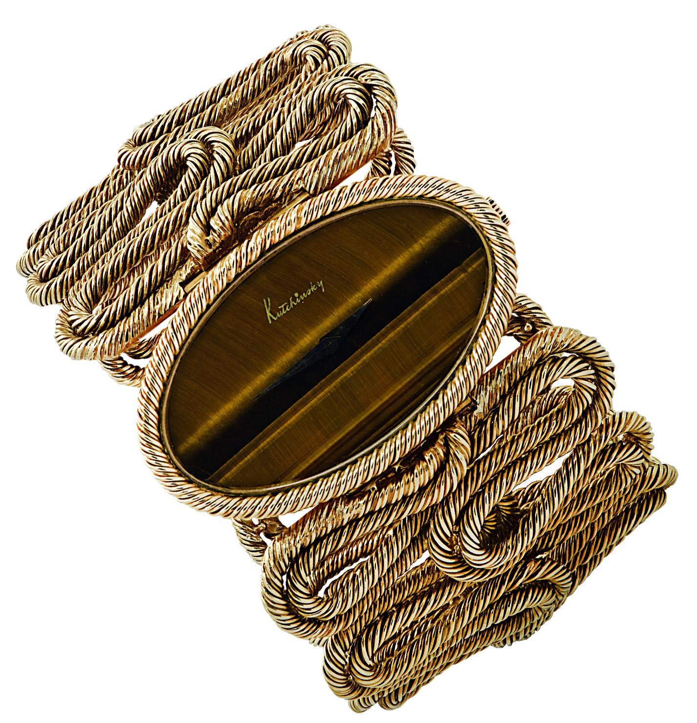 Stunning ladies’ Kutchinsky manual wind cuff wristwatch circa 1970, crafted in 18 karat yellow gold. The Tigers’ eye oval dial with gold hands is framed in twisted yellow gold rope, which swirls around the wrist embracing it in opulence. The case of