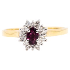 Circa 1970s 18 Carat Gold Oval Deep Red Natural Ruby and Diamond Cluster Ring