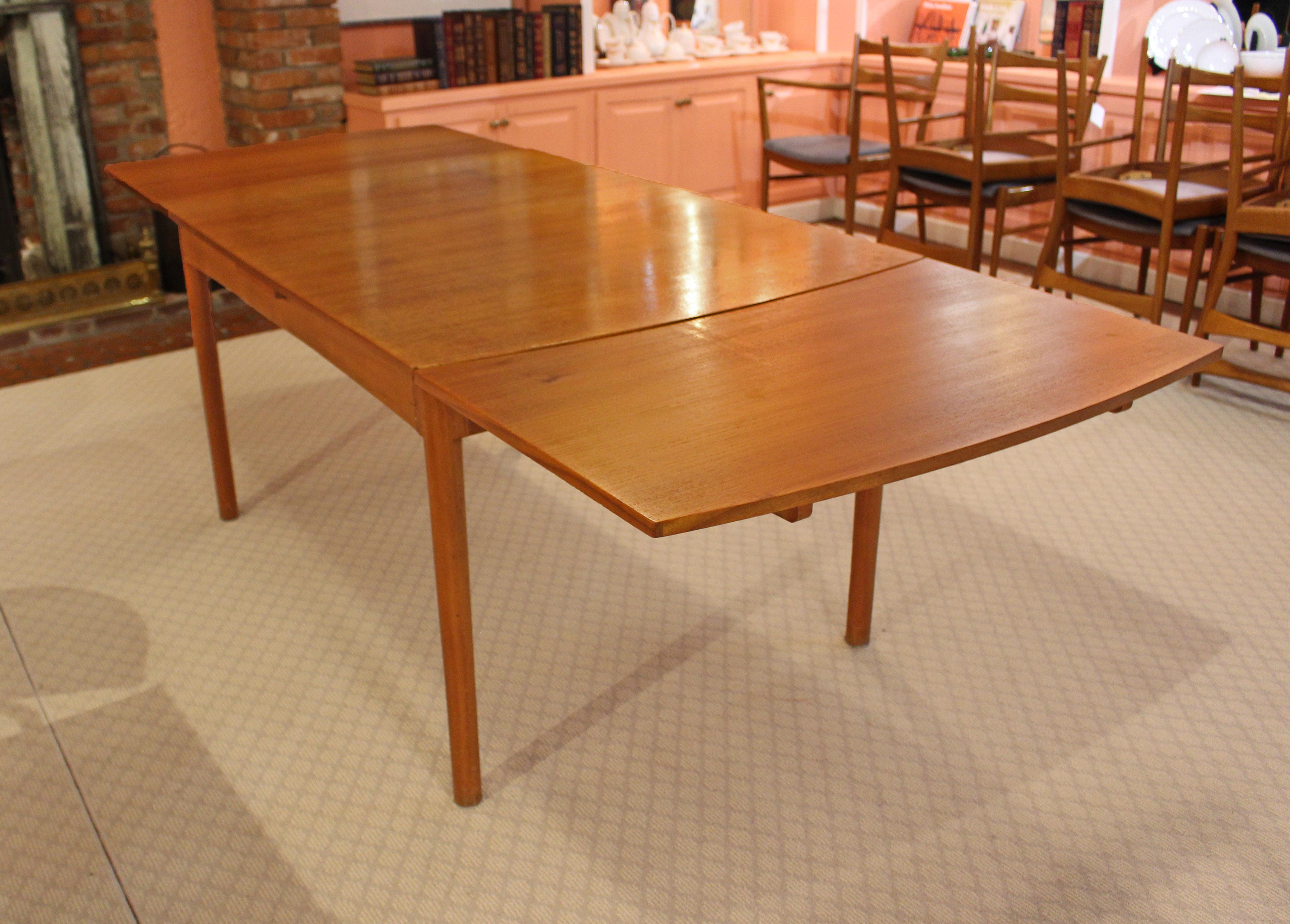 Circa 1970s Mid-Century Modern draw leaf dining table attributed to McIntosh. Made of teak, raised on turned legs. One side rail replaced. Marks & scuffs commensurate with age & use.

Measures: 36