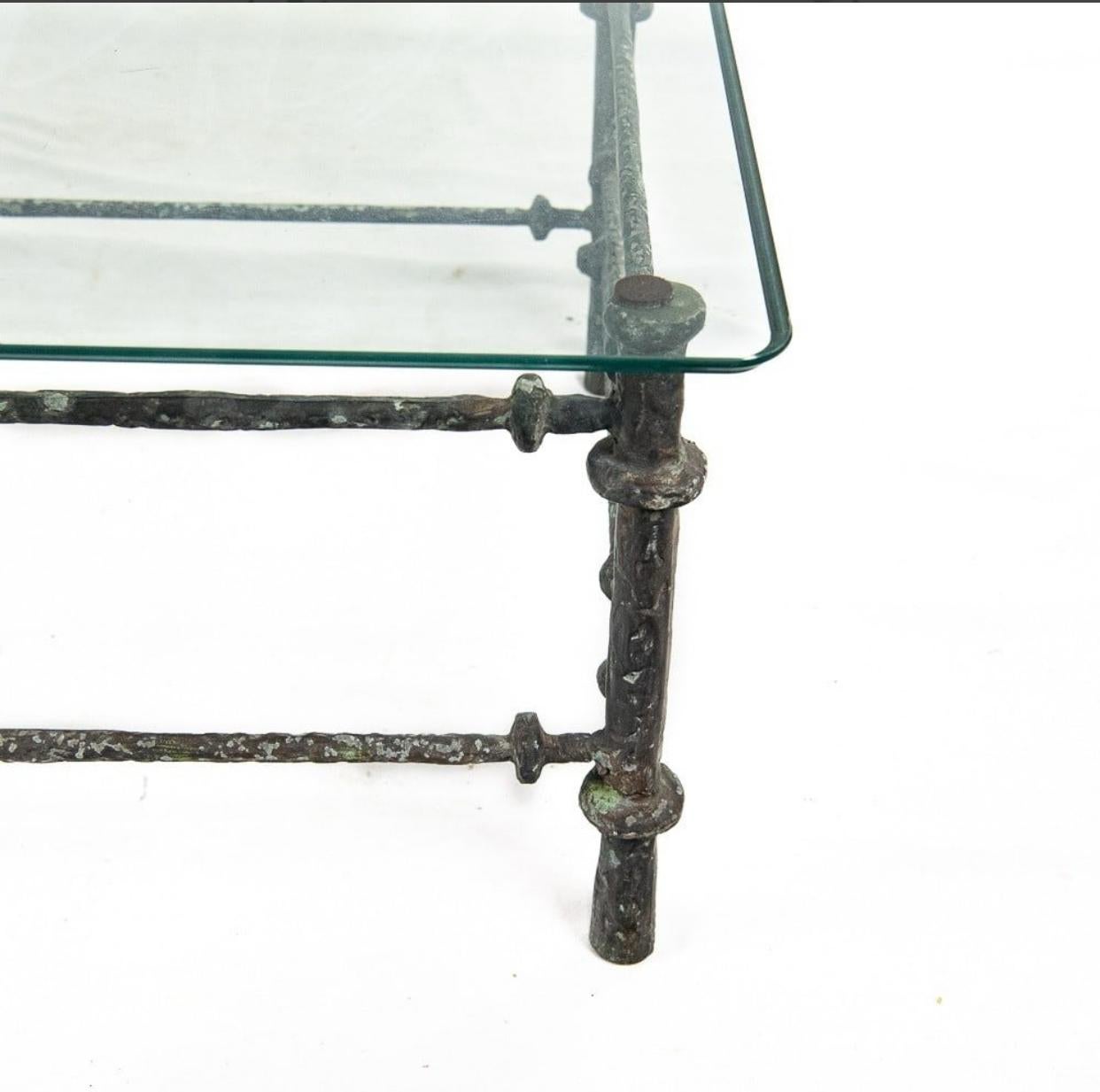 Hammered iron coffee table in the manner of Diego Giacometti. Each leg is supported by a pair of long hammered wrought iron rods with rondels to the front and back. The sides have three shorter rods with matching rondels. The base measures 43”l x