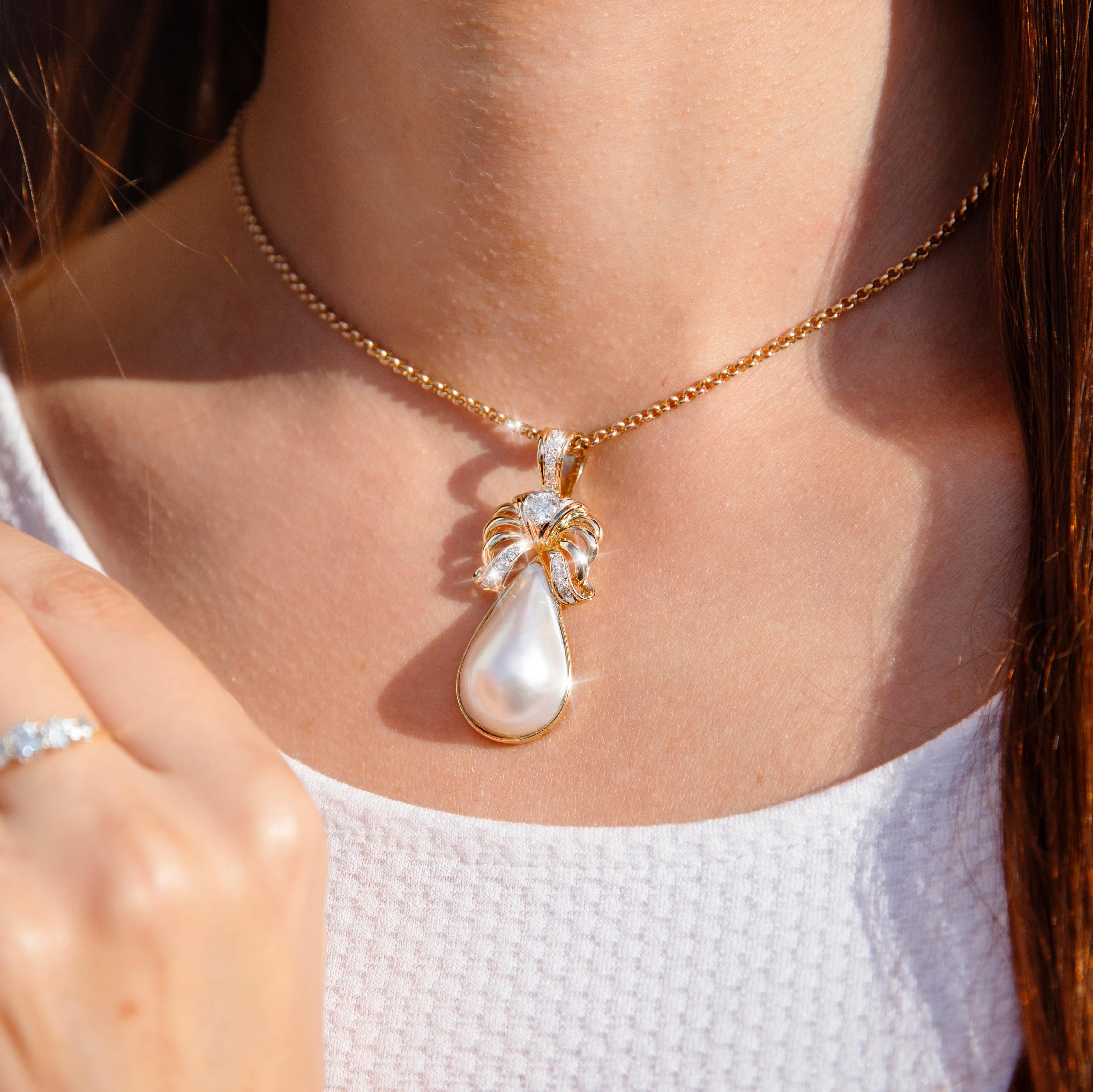 Elegantly crafted in 18 carat yellow gold, this gorgeous vintage enhancer pendant sees a luxurious pear shape mabe pearl in a bezel setting and fitted with an elaborately designed enhancer style bail encrusted with round brilliant cut diamonds. We