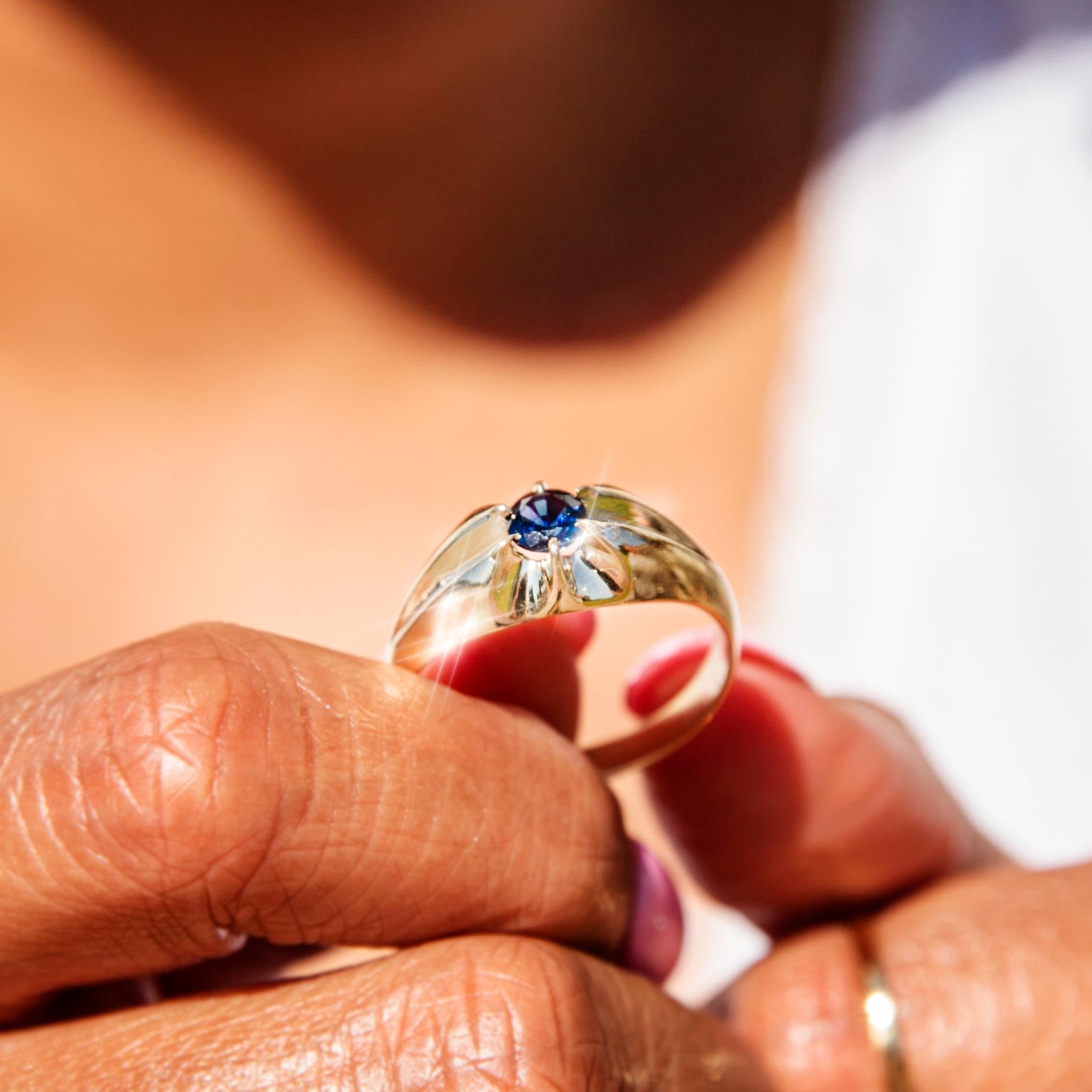 Dieser mit Liebe geschmiedete Ring aus 9-karätigem Gelbgold hat ein hochglanzpoliertes Band, das in eine gewölbte Spitze mündet, und eine gequetschte 6-Krallen-Fassung, die einen schönen, tiefblauen, runden, facettierten Saphir hält. Wir haben ihr