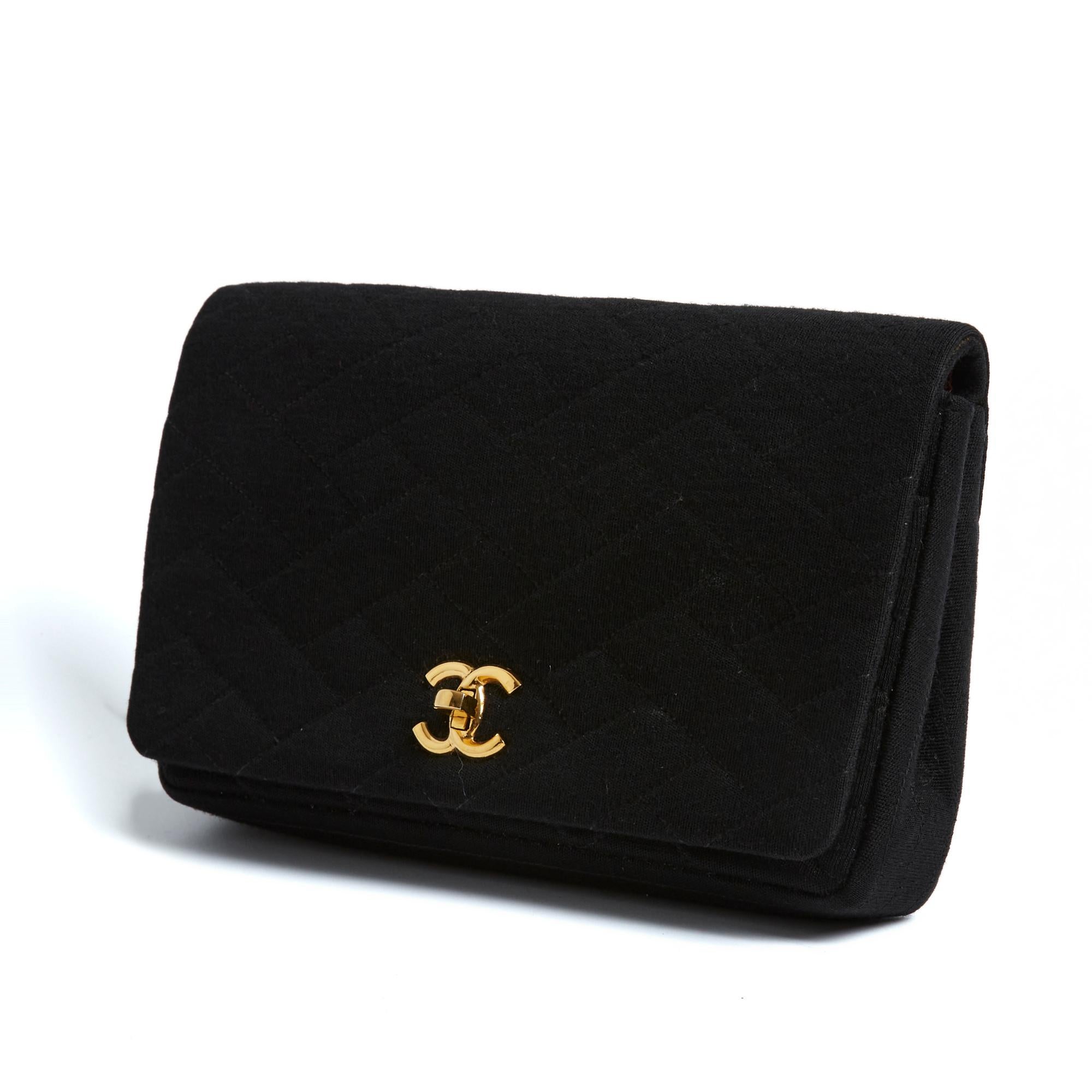 Pochette Chanel série Timeless ou Classique en jersey de laine matelassé noir, rabat avant avec fermoir quart de tour CC ou Turnlock en métal doré, intérieur en cuir bordeaux avec 1 poche zippée et une double poche plaquée, ainsi qu'une grande poche