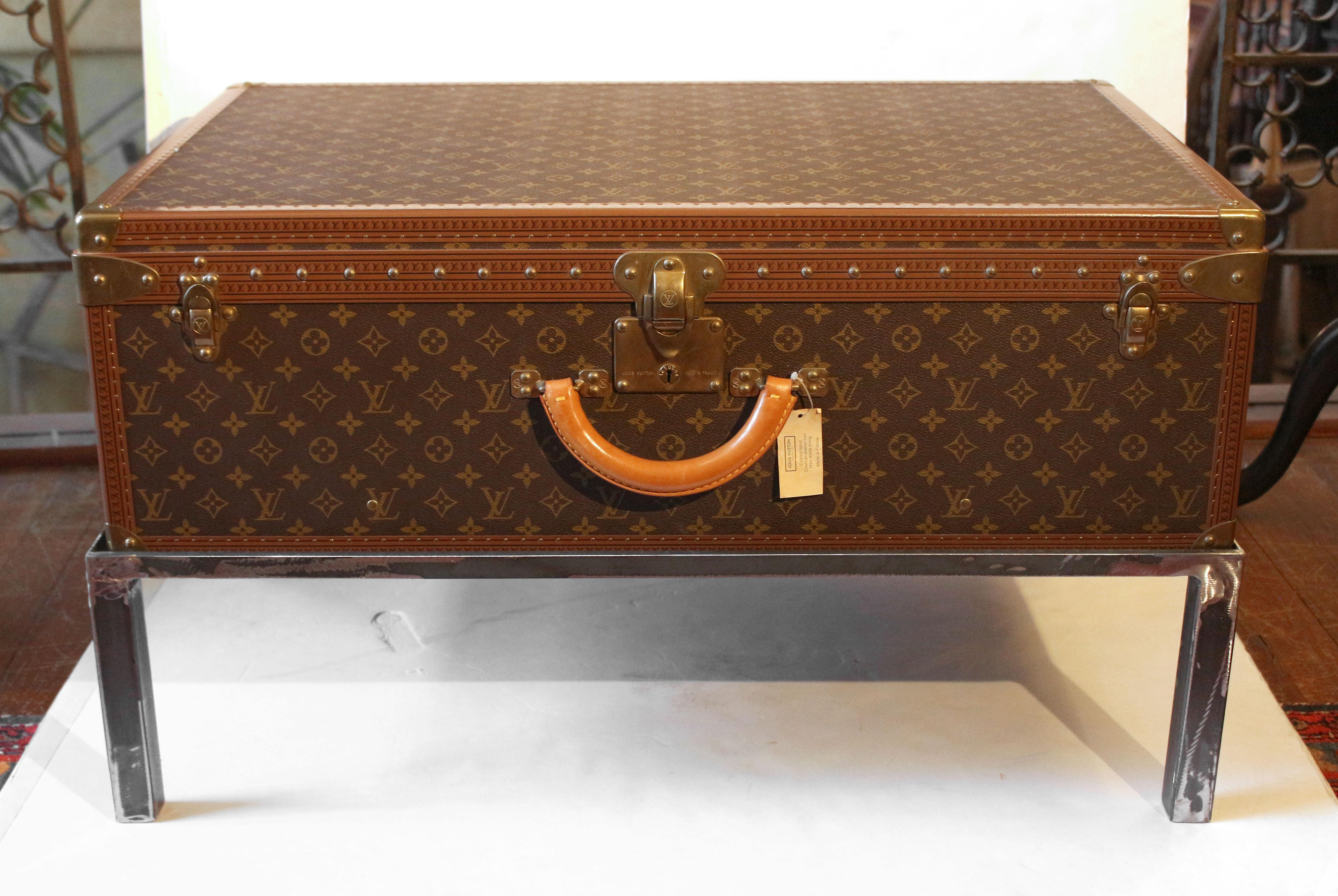 Circa 1990s Louis Vuitton Alzer 80 Suitcase now on custom made coffee table height steel stand. Coated fabric, cowhide leather trim, man-made lining (from original tag). Made in France. Sturdy leather handle. Brass mounts. Case #102163. Very good