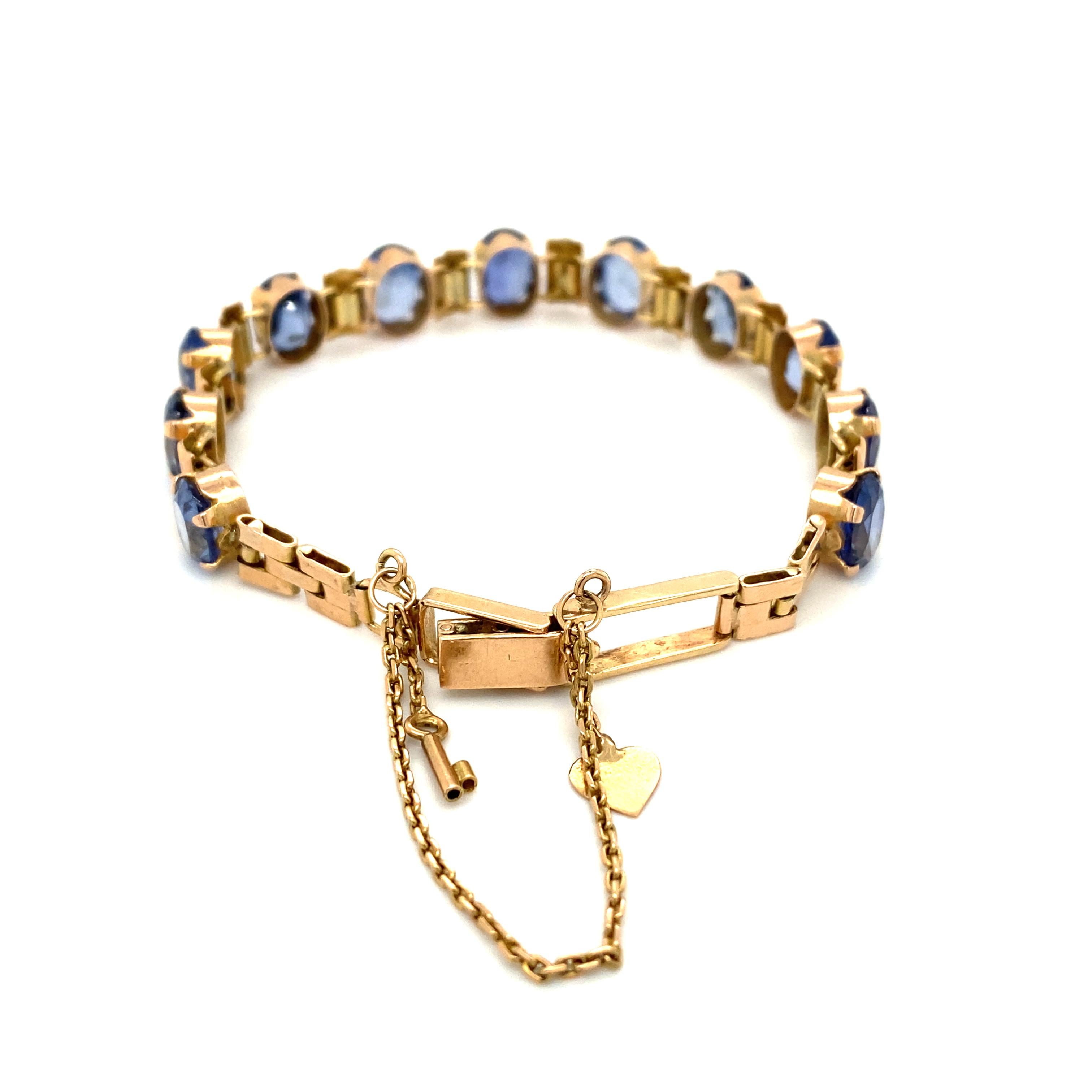 Item Details: This statement bracelet features oval iolite stones with gold spacers. The safety chain has charms with a heart and key. This bracelet is crafted in 14 karat yellow gold.

Circa: 1990s
Metal Type: 14 Karat Gold
Weight: 14.3 grams
Size: