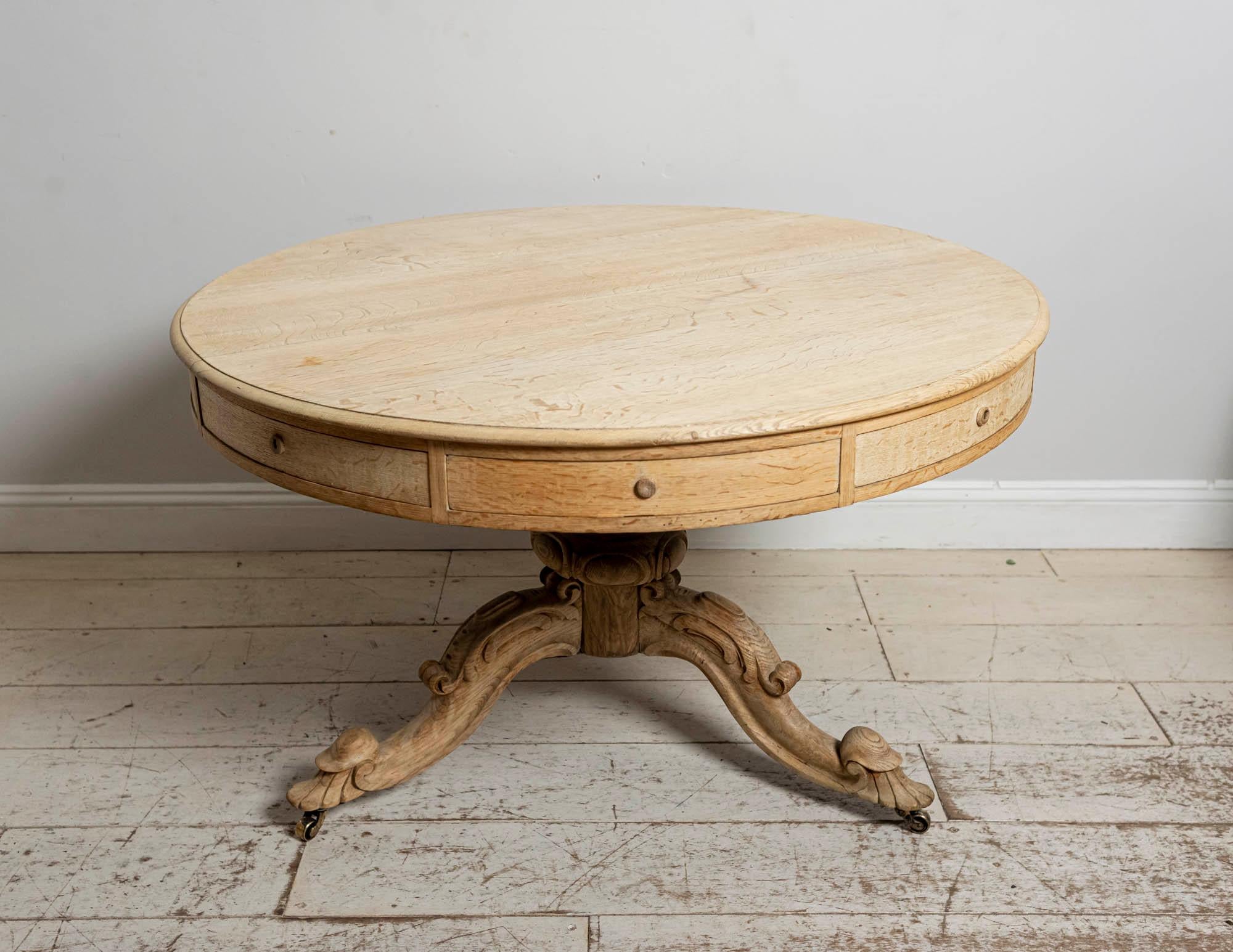 A handsome circa 19th century bleached oak drum or centre table which features eight drawers with flat knob handles. Four of the drawers are false. Set on a pedestal with a carved tripod base. There is a small key for the four drawers 

Perfect as