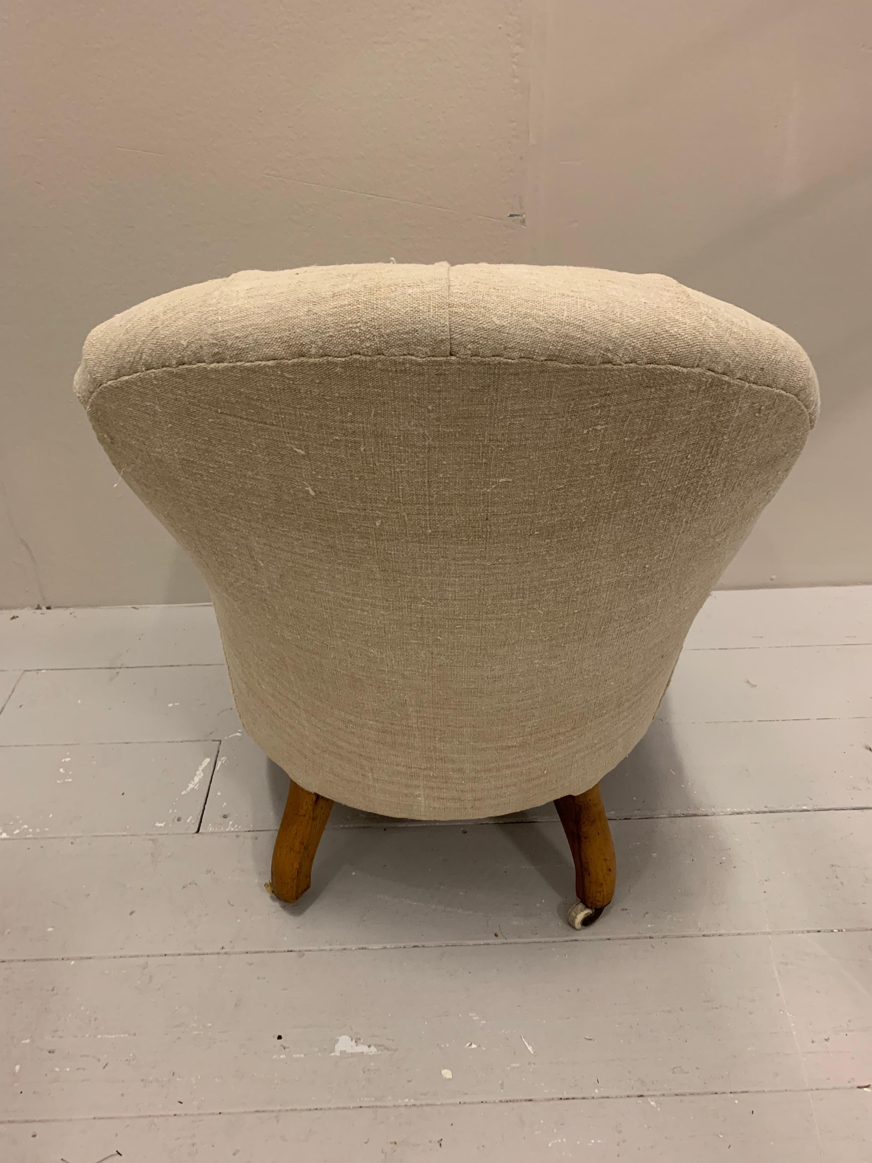 Circa 19th century upholstered English armchair with turned legs and ceramic castors.
This understated buttoned back armchair has been upholstered in a slightly coarse off white vintage french linen.
Great as a fireside, bedroom or reading chair, it