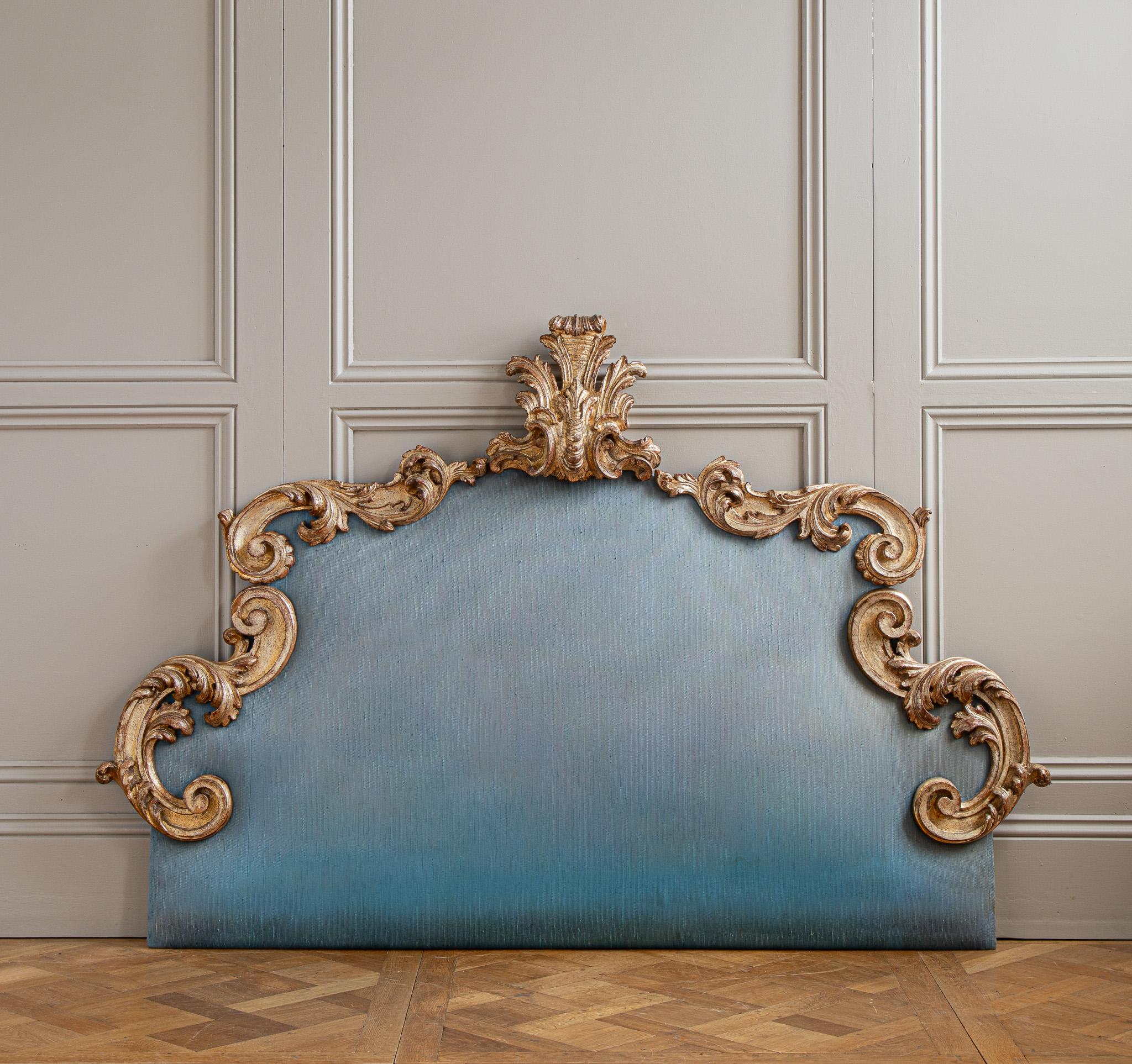 Une grande tête de lit de Florence, Italie, circa 1900, capturant l'élégance ornée de la période Rococo. La tête de lit est composée de courbes en S embellies avec une grande feuille d'acanthe stylisée à son sommet pour le motif central. La pièce