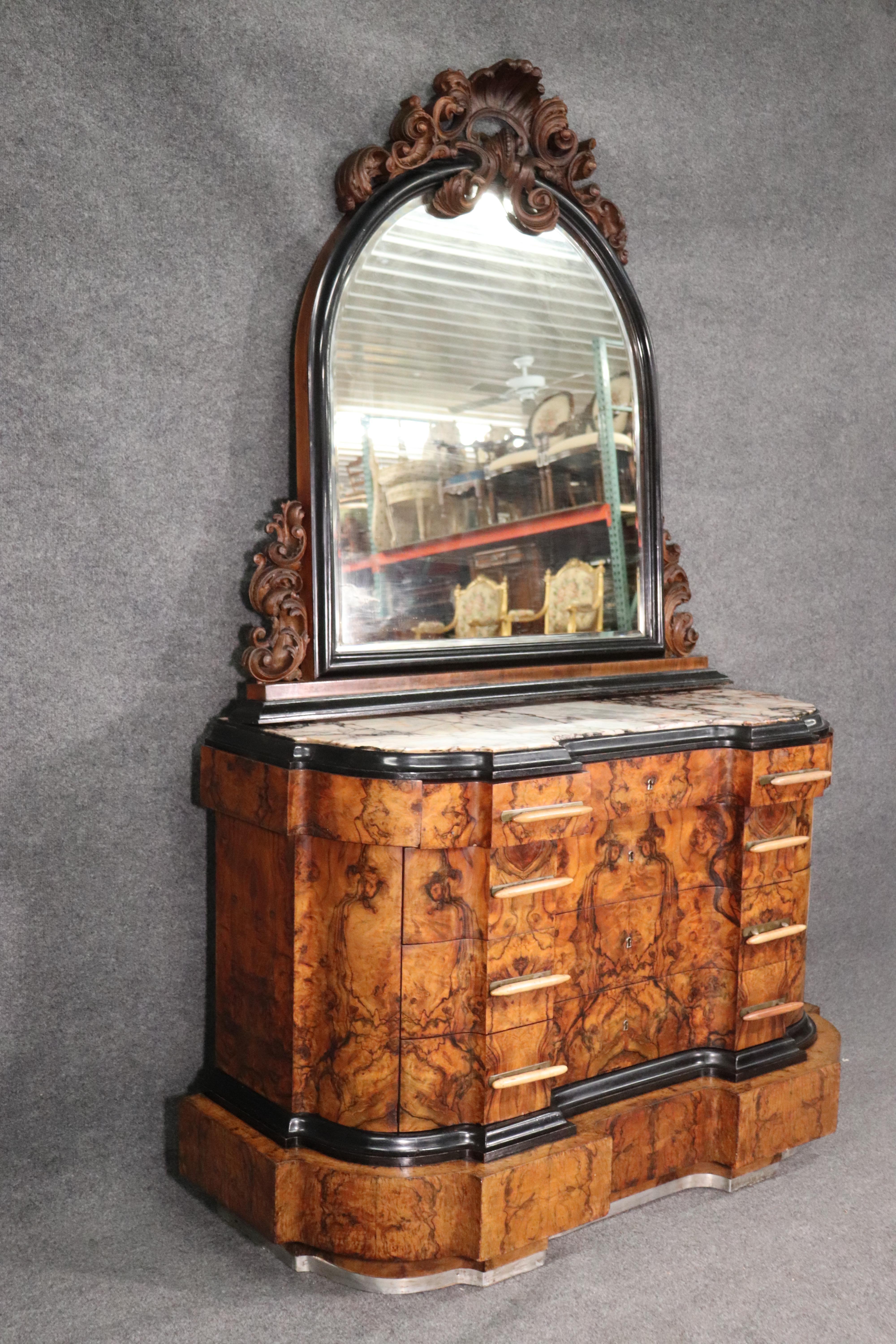 This is a fantastic dresser made during the Art Deco era of the 1920s and features a fantastic circassian walnut case and varigated marble top. The top was professionally repaired at one point in its life and is not noticeable. The mirrored top is