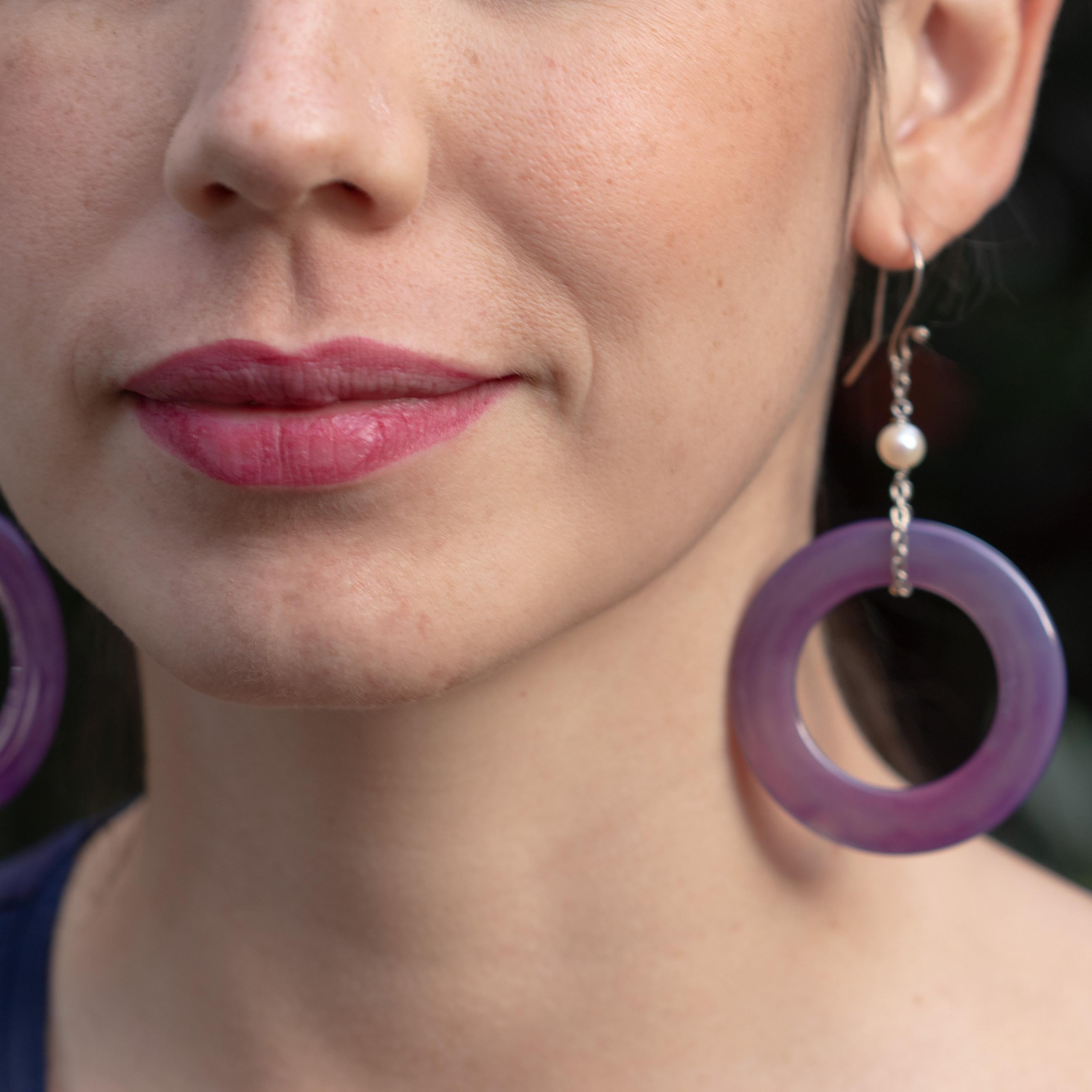 Kreisförmige funkelnde Ohrringe aus lila Achat und Süßwasserperlen. Lila Donut-förmiger Achat mit Farbverlauf, gehalten von einer 925er Sterlingsilberkette mit einer runden Süßwasserperle an der Spitze. Zeitgenössisches und einzigartiges Stück, das