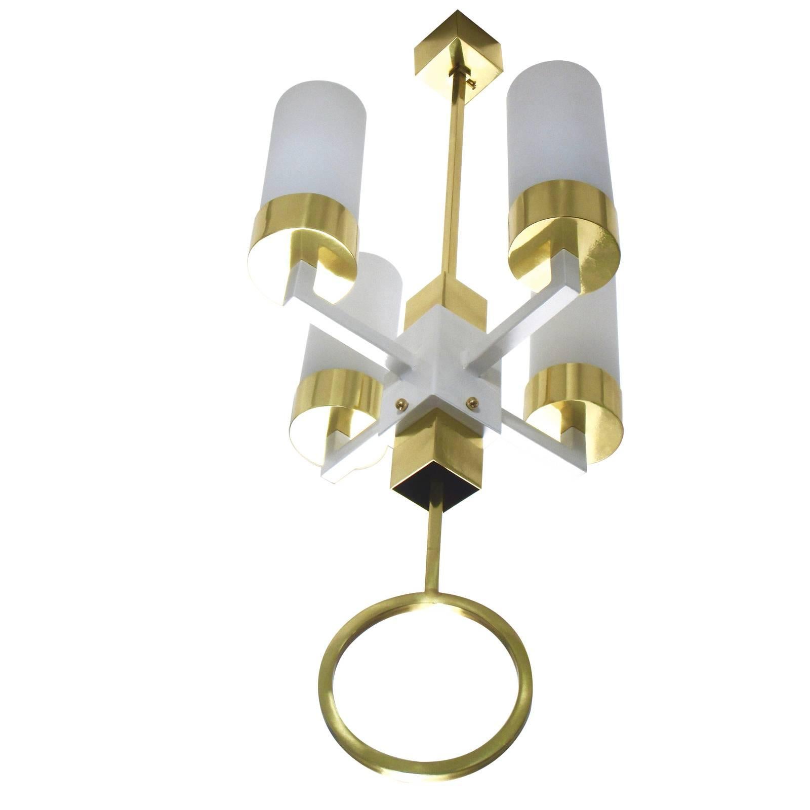 The perfect centrepiece in an entryway, dining room, and loft space, the peculiarity of this chandelier is the large brass circle suspended from the bottom finial that creates a balance of modern lines and traditional elegance. Four L-shaped arms