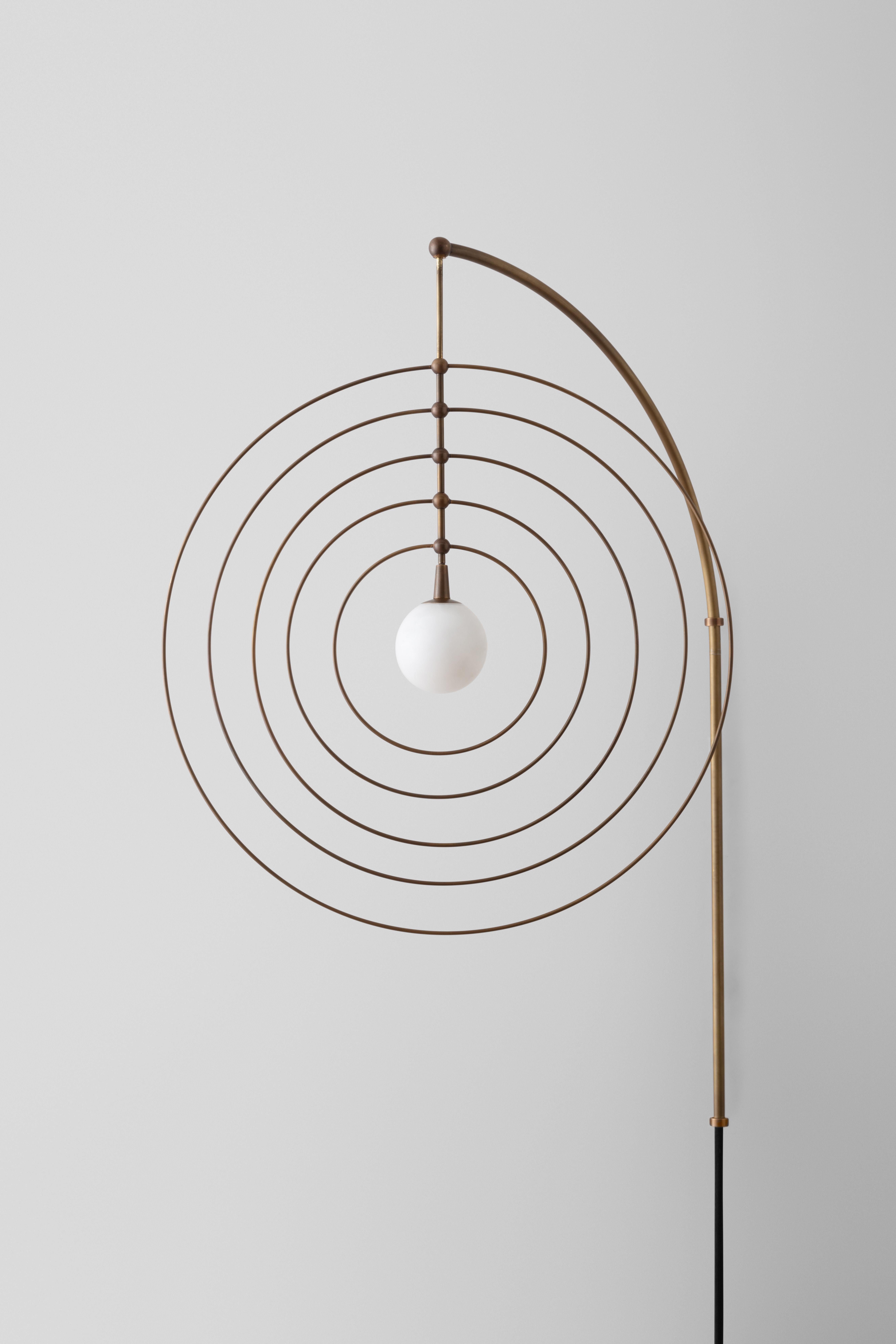 The Mobile series combine sculpture with lighting, invoking motifs from atomic models and the space age. The concentric rings can be spun and reconfigured, inviting play and whimsy. The central orb illuminates the brass rings, which are
