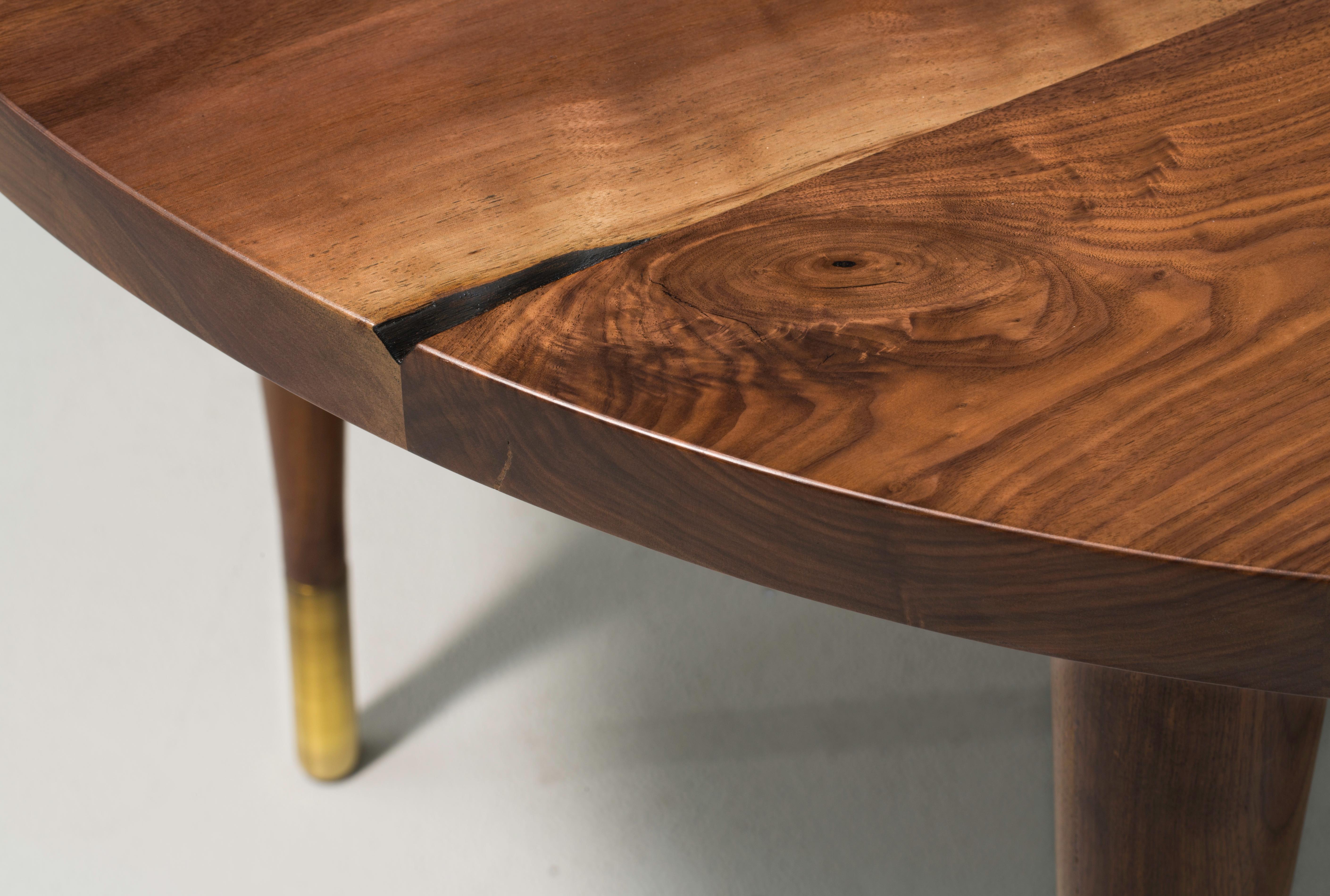 The Warren dining table is an expanding circular dining table made of solid walnut boards. The simple and sleek tapered legs are capped in brass to add elegance and style to the table. With added leaves to the table, it has the versatility to fit