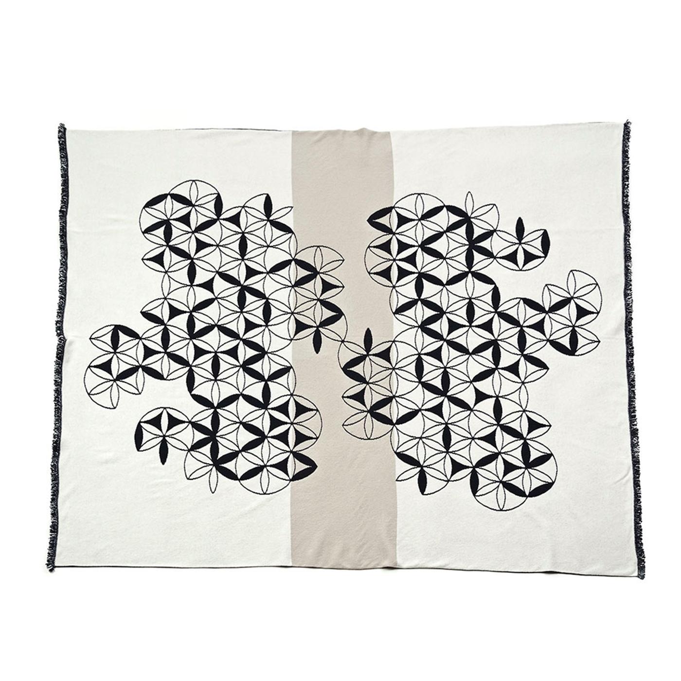 A series of geometric motifs are connected together in an abstract pattern to create a mesmerizing white motif that stands out over the dark grey of the background with a unique sense of movement. This jacquard knit decoration gives the blanket a