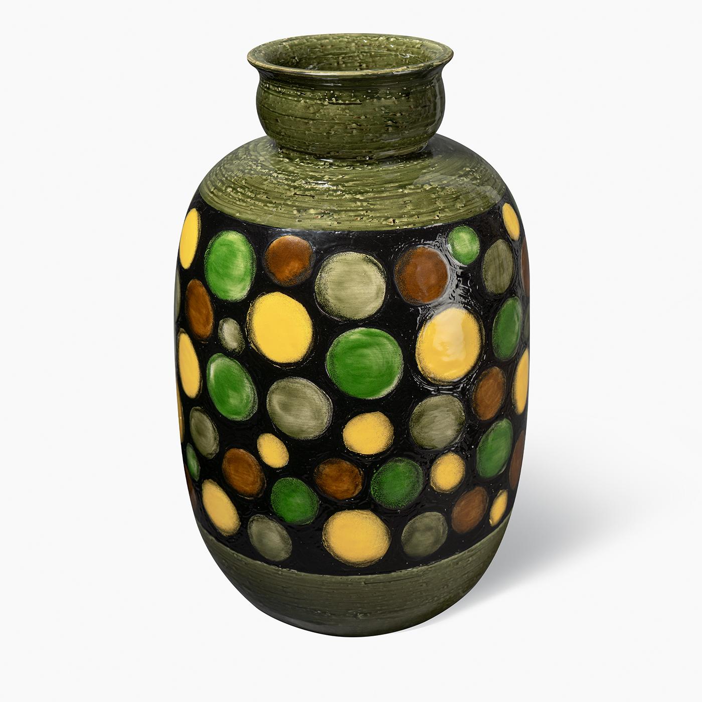 This decorative vase features a turned form in red clay with a vibrant series of colored circles hand-painted in yellow, green, and black over an olive-green base and rim. The glossy finish enhances the bold contrast and texture, creating a striking
