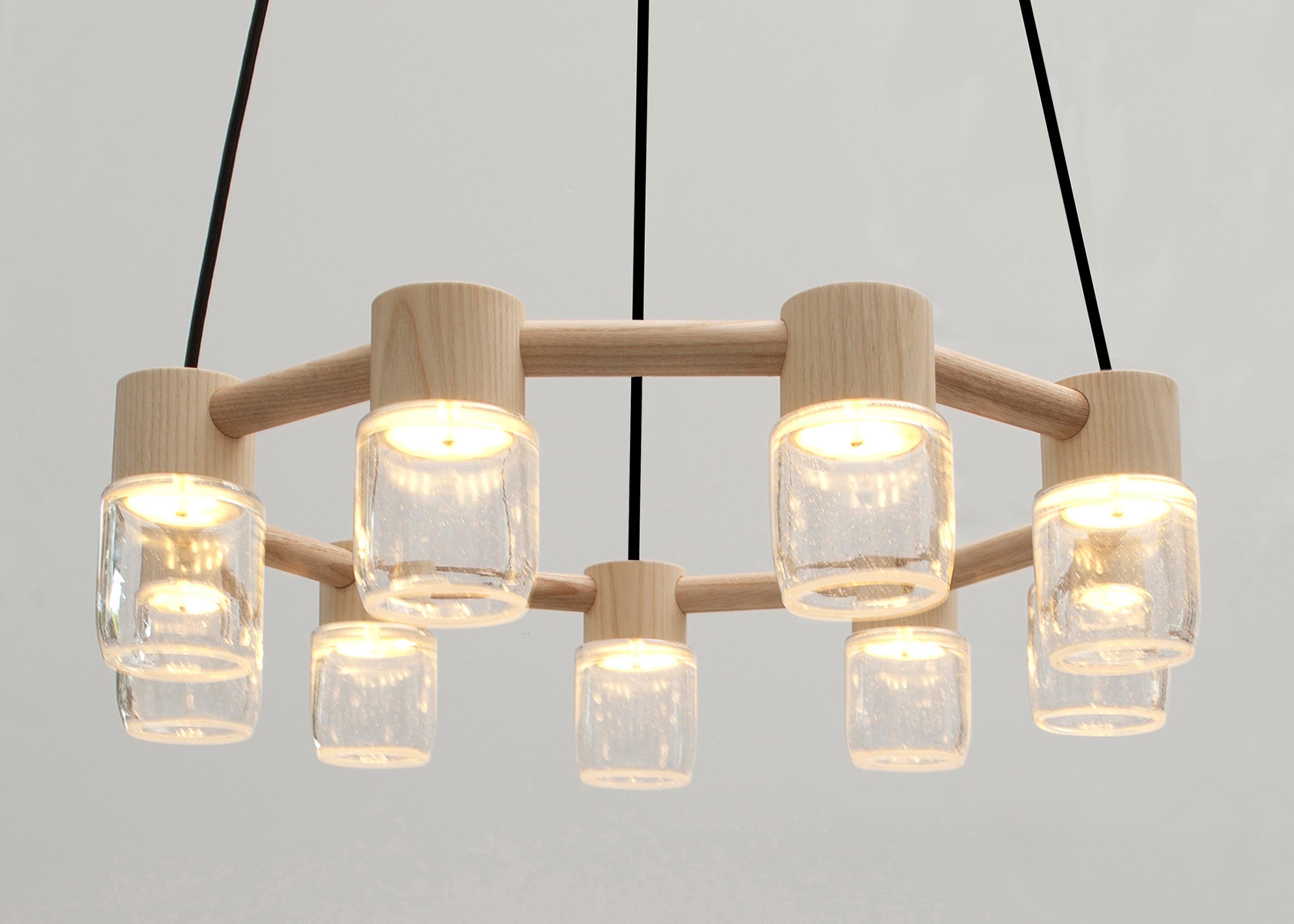 This handmade chandelier pairs a minimal solid wood canopy with nine hand blown glass diffusers. Efficient LED lighting components are neatly hidden in each canopy allowing the glass diffusers to illuminate without a visible bulb. 

Built in the