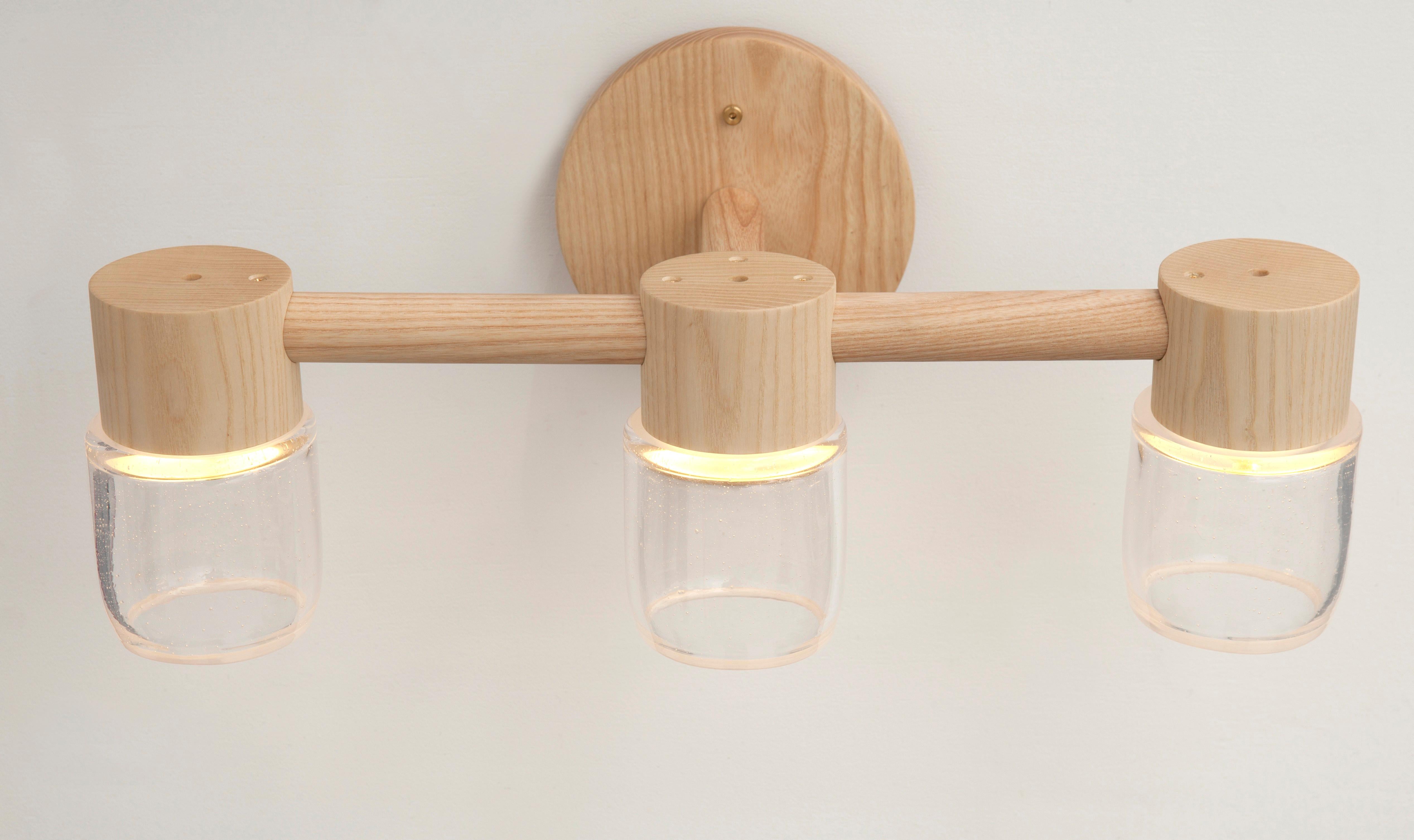 Diese handgefertigte Leuchte kombiniert einen minimalistischen Baldachin aus Massivholz mit mundgeblasenen Glasdiffusoren. Effiziente LED-Beleuchtungskomponenten sind in jedem Baldachin versteckt, so dass die Glasdiffusoren ohne sichtbare Glühbirne
