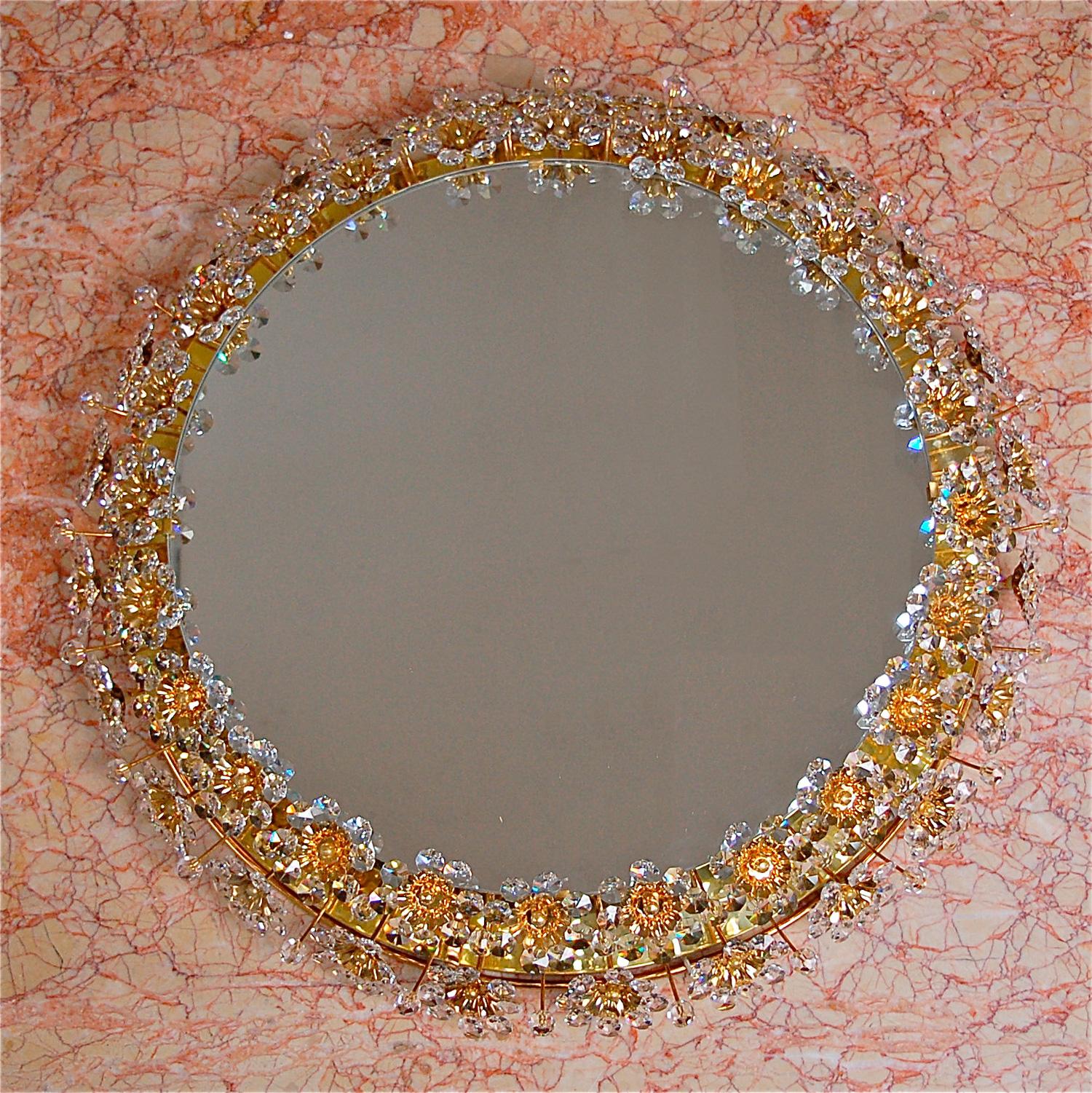 Mid-20th century illuminated circular mirror by German manufacturer Palwa. The mirror is framed with a double border of delicate flowers and petals made from faceted crystals and beads that sparkle in the light. The frame is made from gold colored