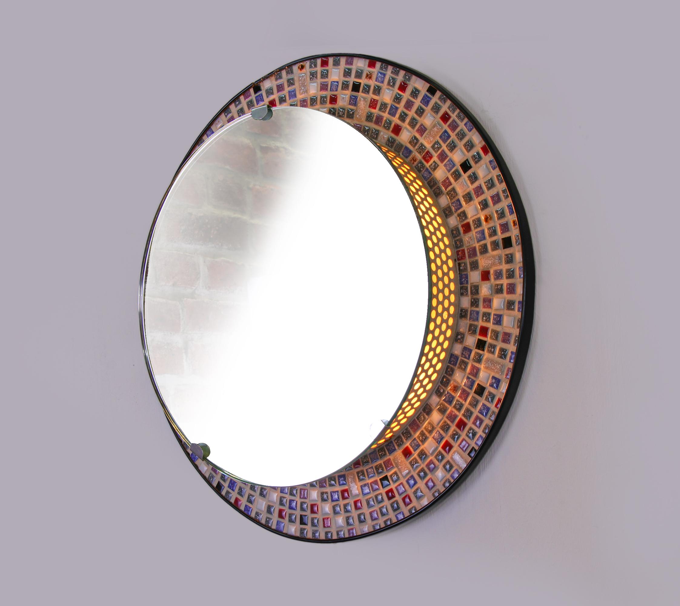 Highly decorative wall mosaic mirror with a illuminated background. Manufactured by Hillebrand attr. in Germany, 1950s. 

The mirror is mounted on a perforated metal base, the lighting is hidden behind it and it is edged with multicolored porcelain