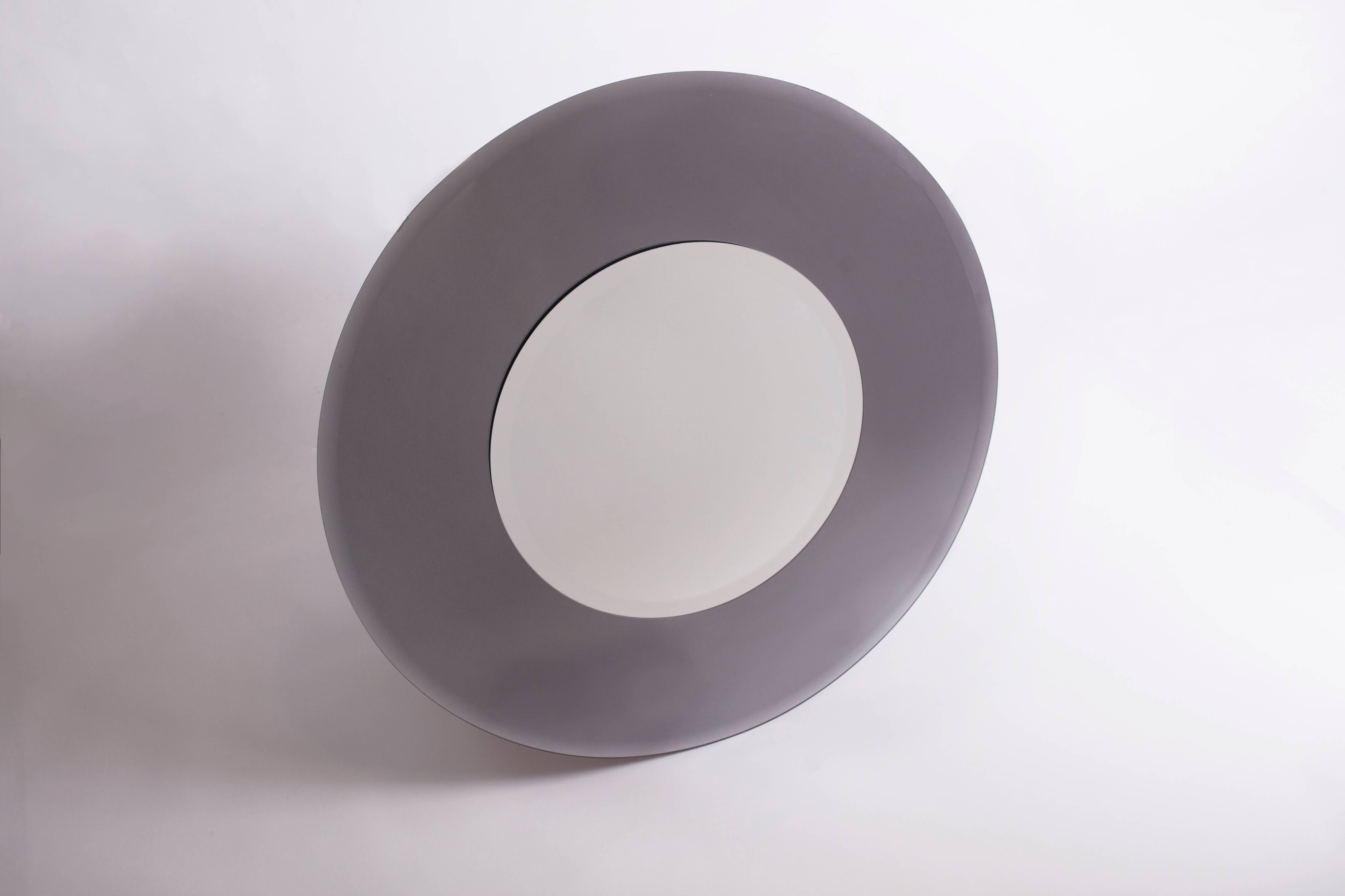 Un grand miroir circulaire bicolore italien des années 1970 avec un cadre biseauté inhabituellement profond en verre fumé gris, dans le style de Max Ingrand pour Fontana Arte. 
Excellent état, sans rayures ni éclats.
Mesures : 36'' Ø x 1'' D.