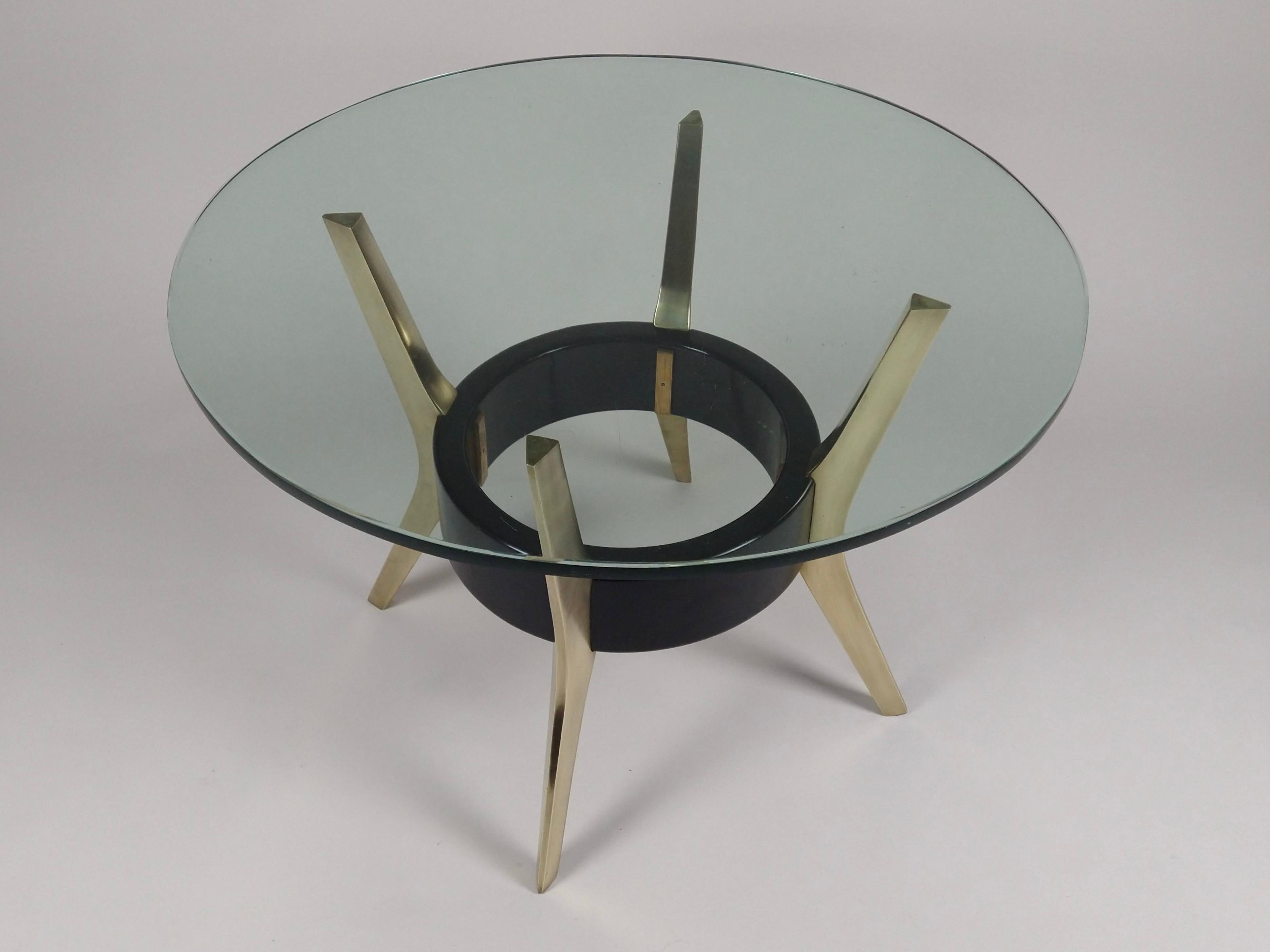An Italian, circular black-lacquered coffee table with a thick beveled glass top. Four solid brass curved leg supports are held together by a circular ebonised stretcher within the frame. A fine quality mid-century side table.