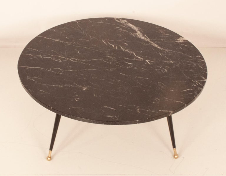Circular coffee table. Structure and four legs in black lacquered iron and feet finished in brass. Marble top,
circa 1990s.