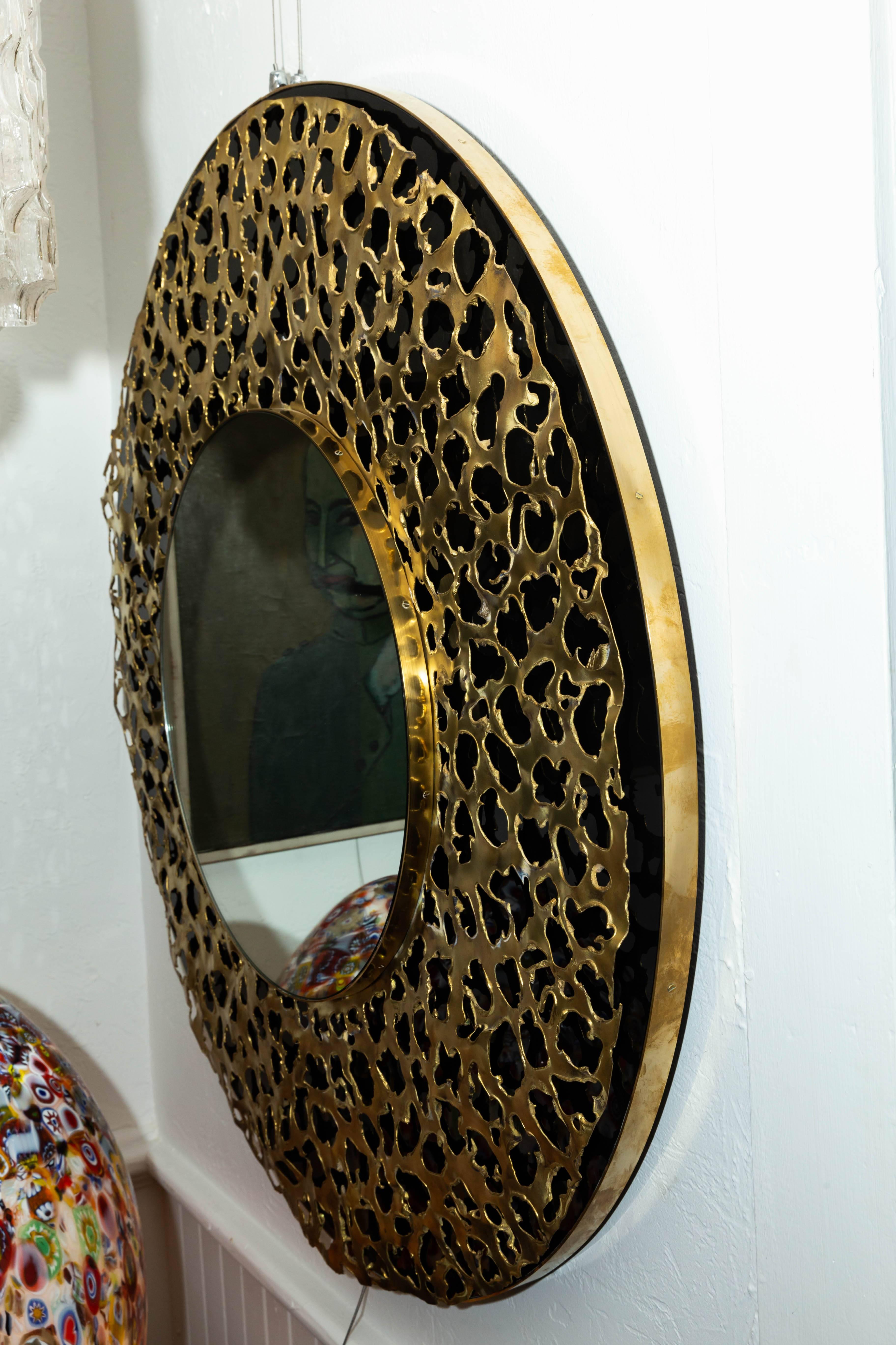 Circular black mirror with brass Brutalist design.