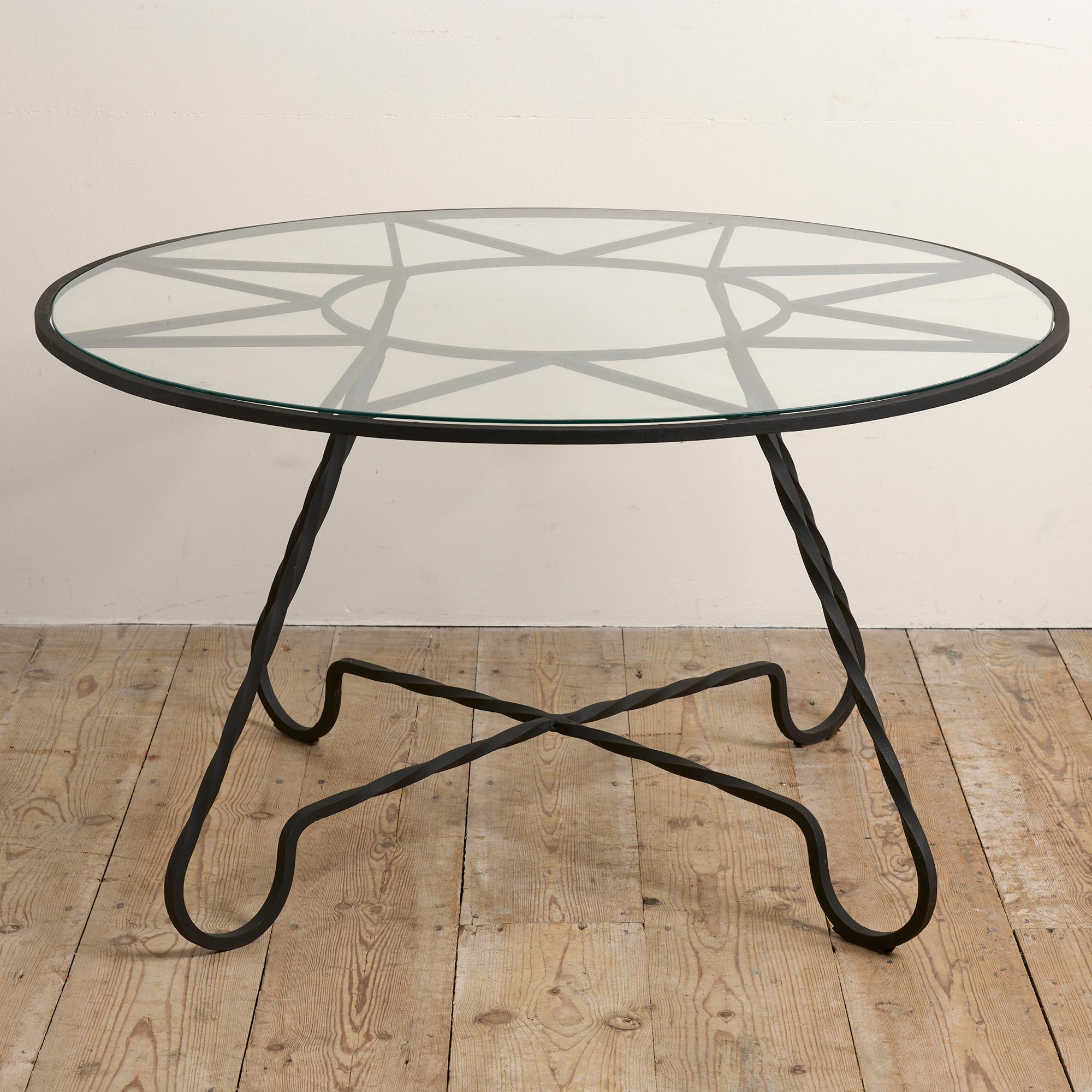 Circular coffee table in black wrought iron with great sunburst / starburst design under the glass top. Stylish crossed base. This table is very reminiscent of the work of Jean Royere who was one of the leading designers in post-war France, he