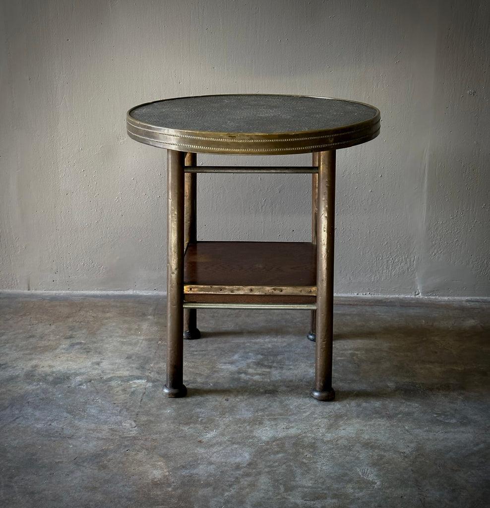 Beautiful brass side table from 1900s France with circular top with pebble textured leather surface and four-footed base with square lower shelf. Simple lines and a great patina make this a highly versatile industrial piece. 

France, circa