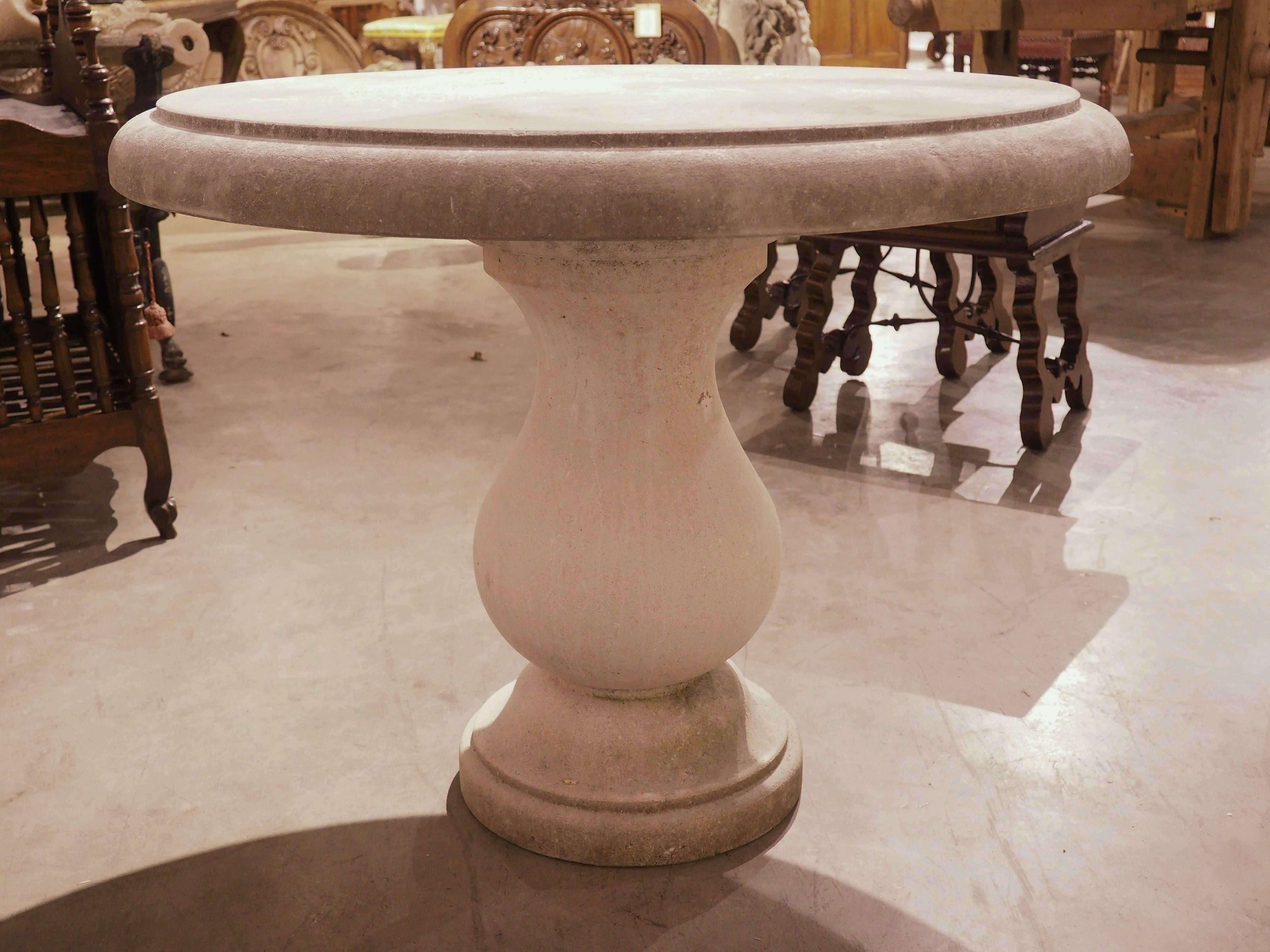 From Italy, this circular hand-carved limestone table has a baluster form base with a molded circular plinth. The three-inch-thick top has a recessed quarter round molding. Perfect for indoors or outside, this charming stone table can be used as a