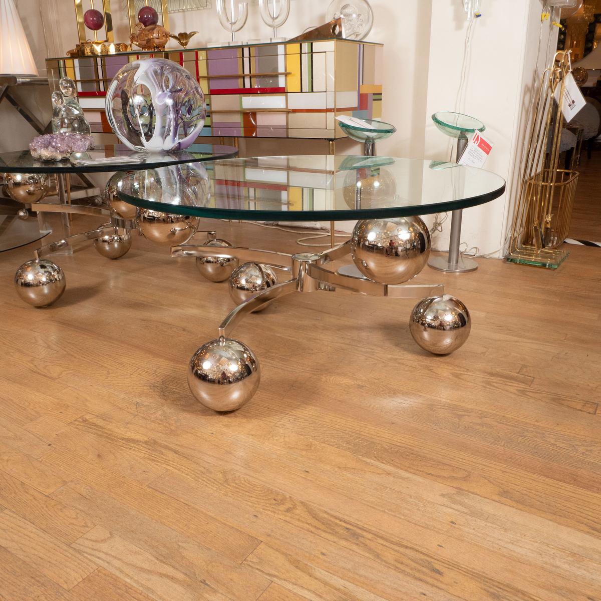 Circular coffee table with nickel base featuring ball form elements and glass top. 