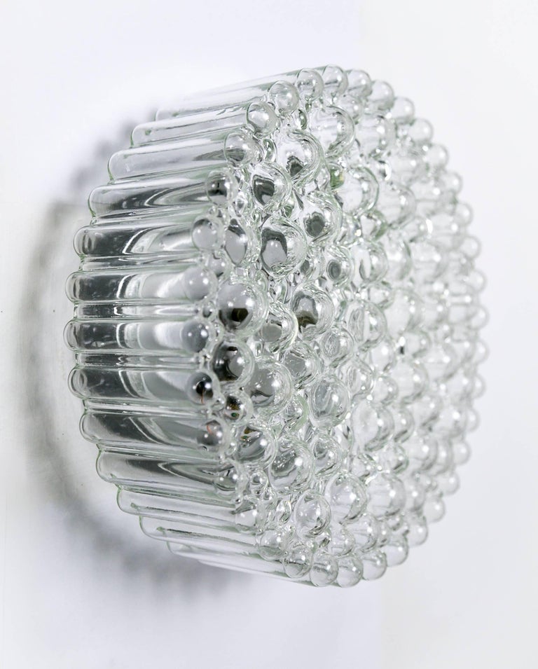This gorgeous sconce designed by Helena Tynell for Glashütte Limburg has a beautiful design of various sized, crystal clear, glass bubbles; with a streamlined, ribbed appearance when viewed from the side. Lovely as a wall or ceiling mount. It has