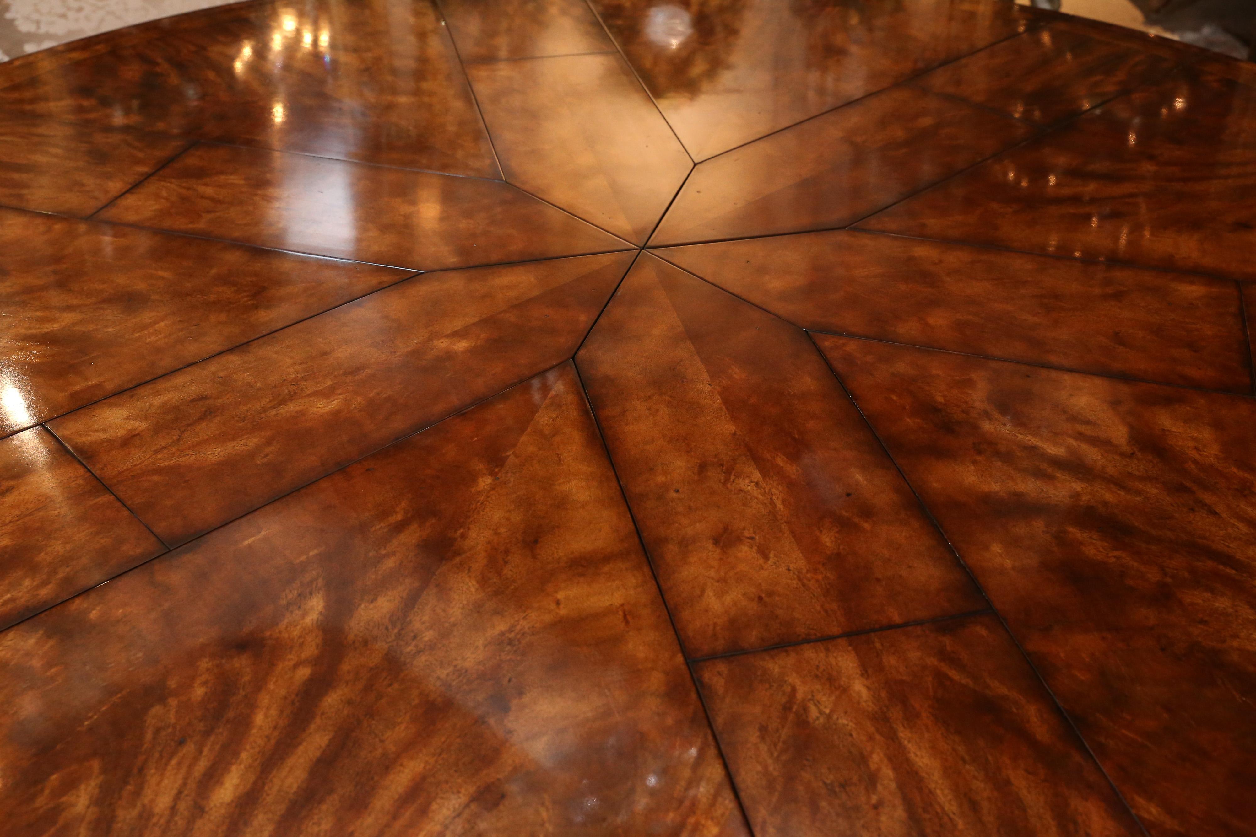 Mahogany flame dining table by Theodore Alexander 
The top is formed of eight pull out triangular segments 
with inset fold out leaves to expand the table, raised on
bold turned pillar with hexagonal base with concave sides
and out swept legs