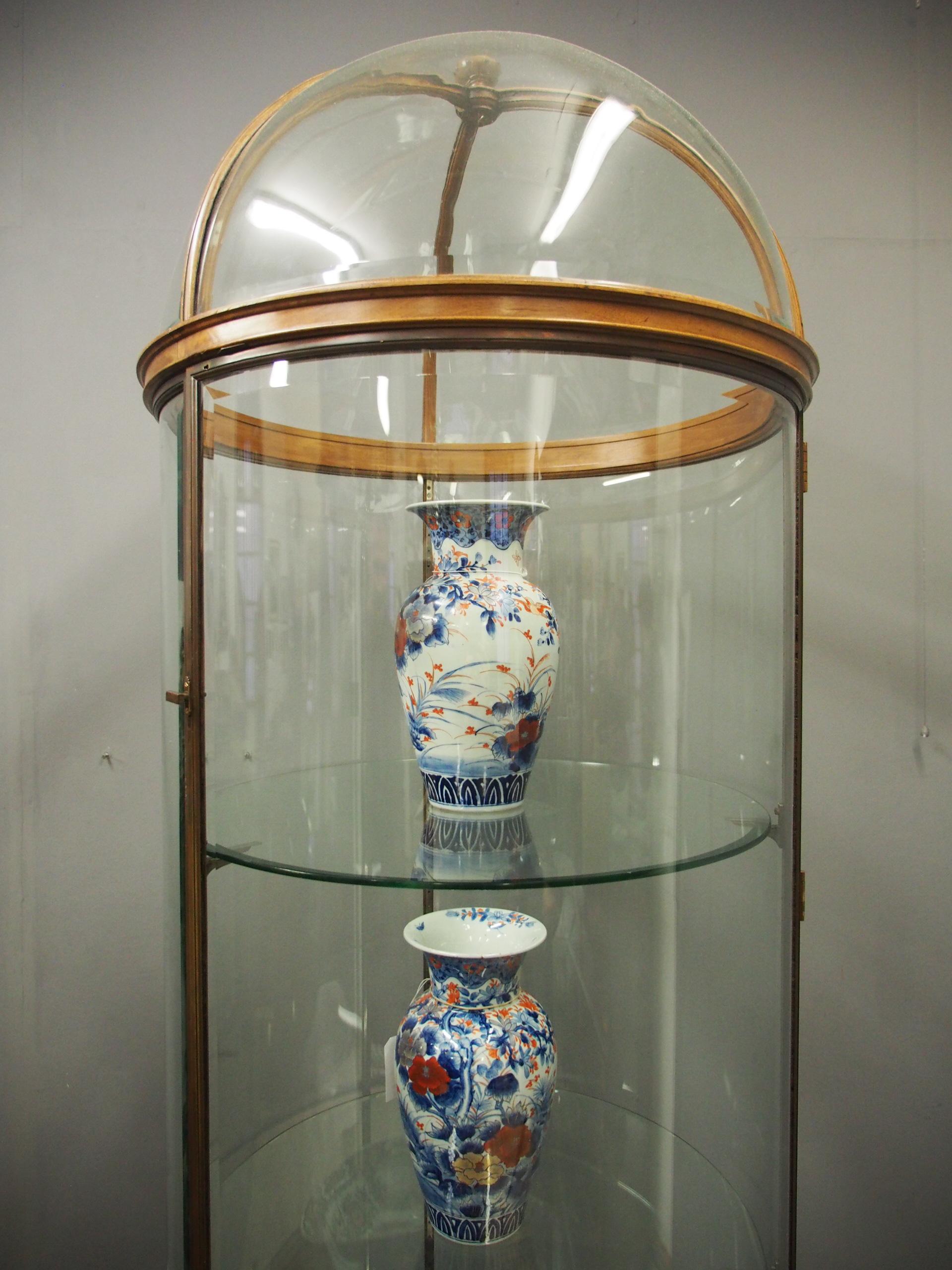 An early 20th century, exhibition quality, walnut and bronze display cabinet. Of circular form with bevel edge glass door and panels, all contained in a bronze frame with a domed, wooden-framed top. Inside are adjustable bevelled edge glass shelves