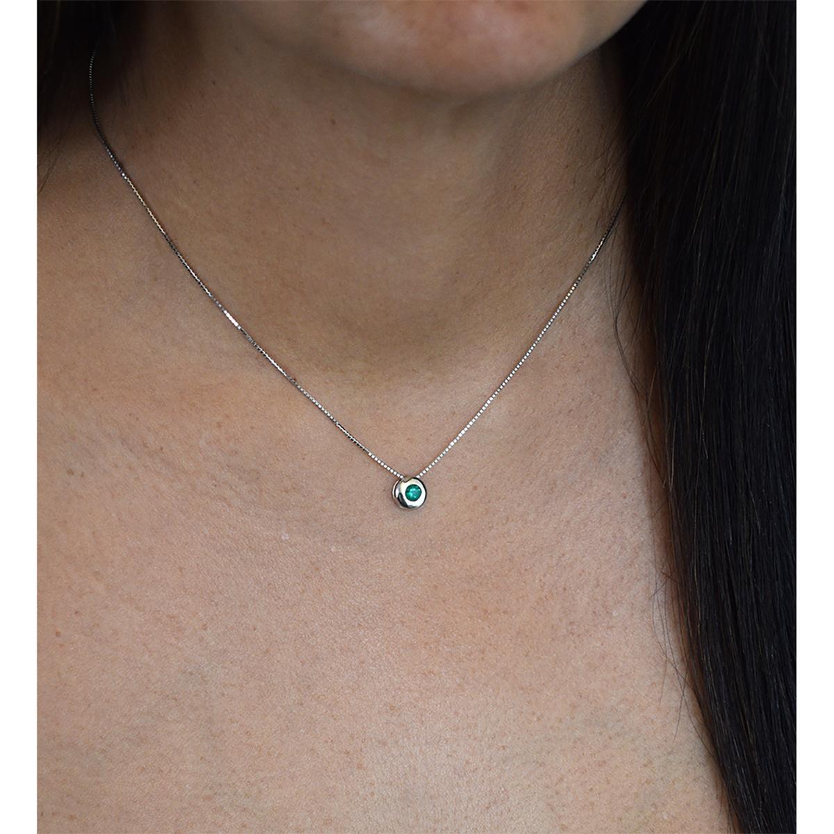 18K white gold solitaire emerald necklace with 0.25 carats round cut real natural emerald in bezel setting. The smooth style and the high polish finished of the gold around the emerald, creates the perfect background for the vivid green color of the