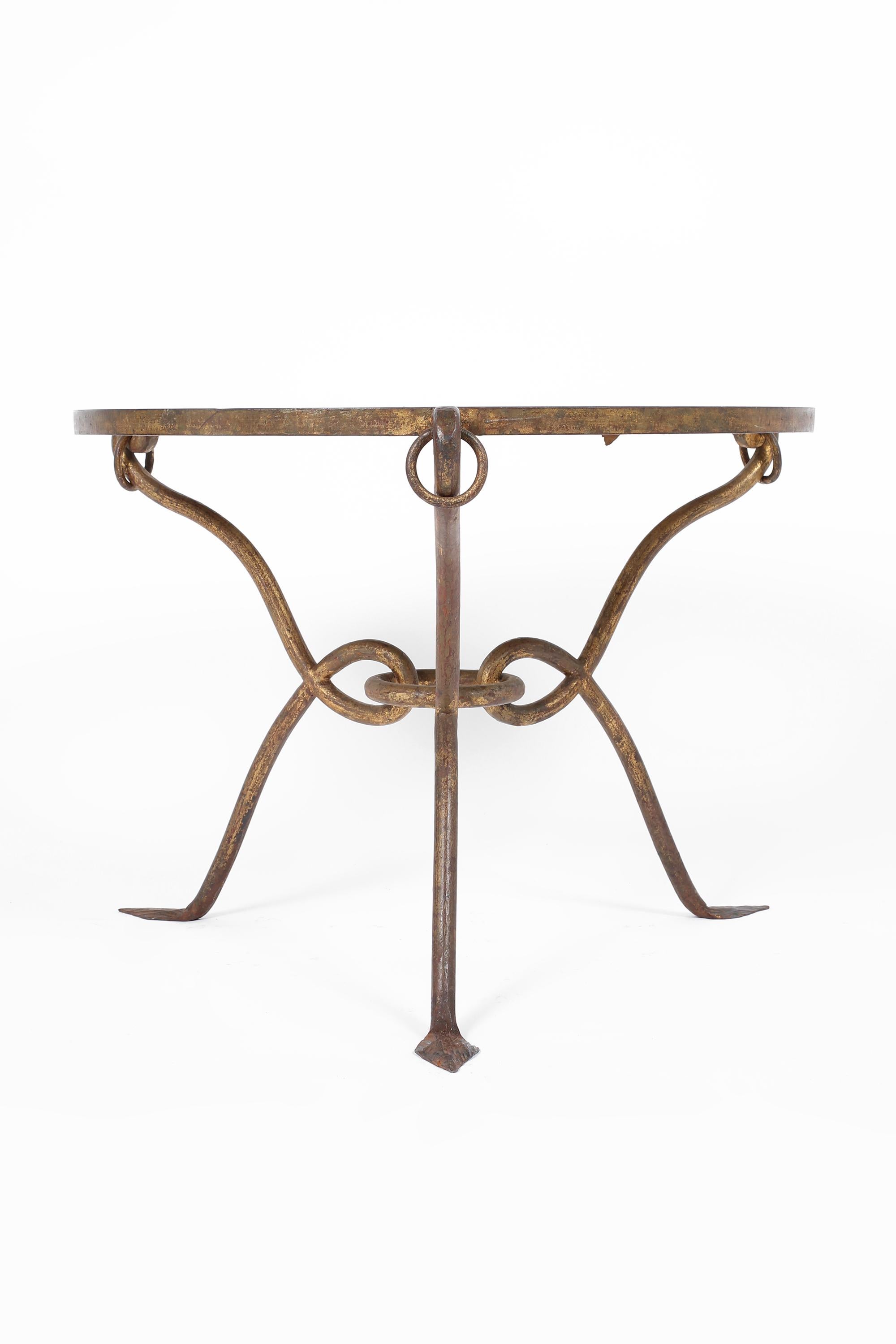 A circular side/occasional table by René Prou (1887-1947), with a gilt forged iron frame and original foliate églomisé mirror glass top. French, c. 1940.