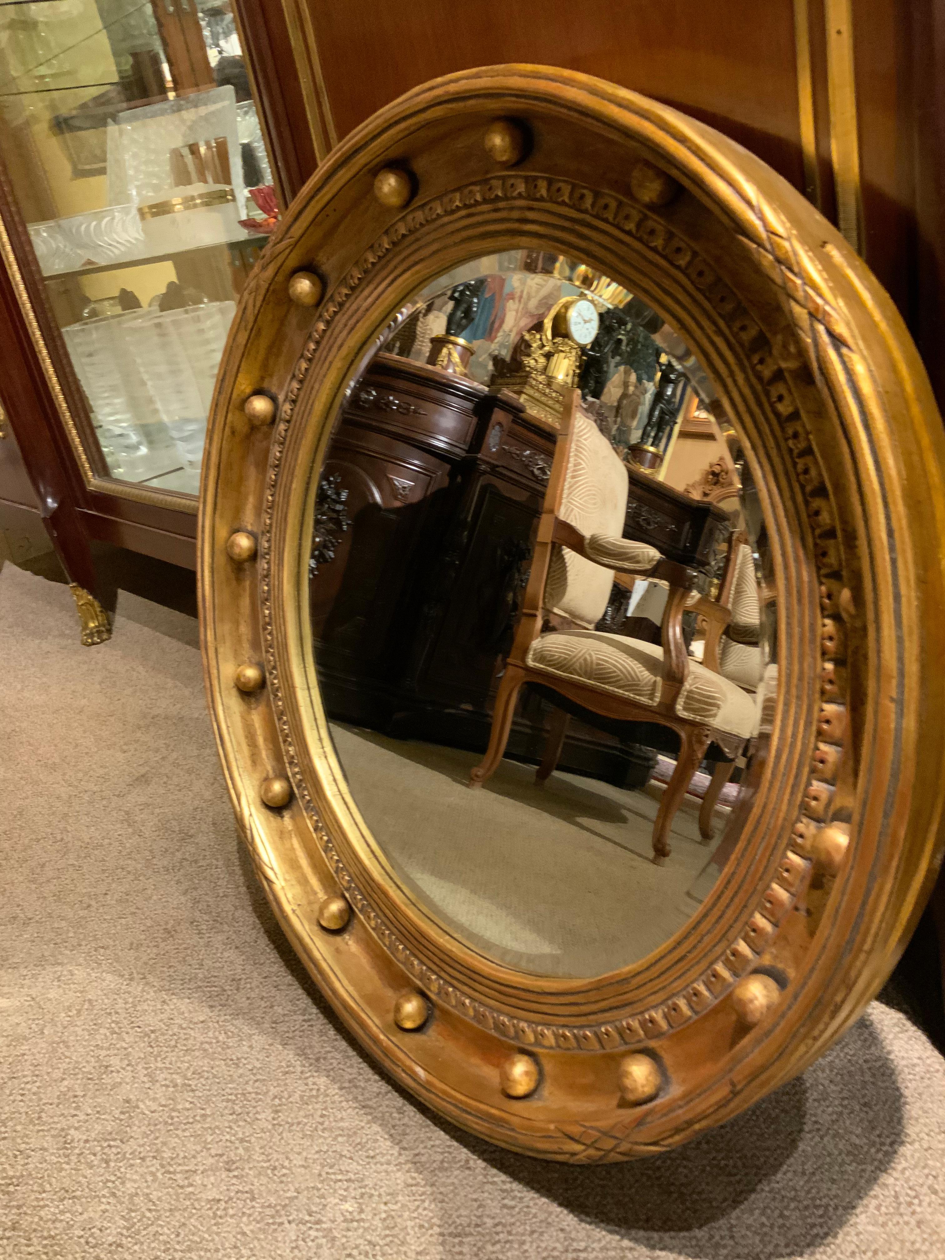 Circular giltwood frame with Grooved carved edge with a rim encircling the edge with
A round ball-like design. And a carved crown design within the inner edge holding
The mirror with a beveled mirror plate. A wire hanger makes this great piece
