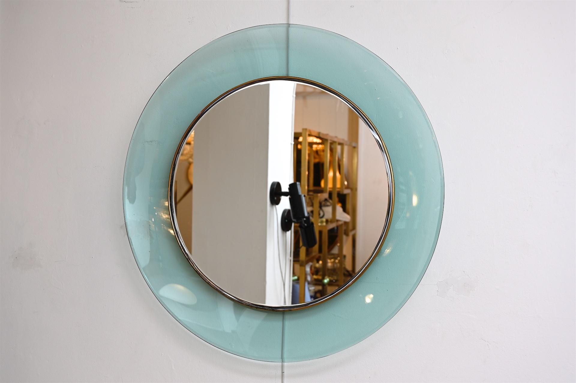 Circular mirror by Max Ingrand, circa 1960. Model 1669. 

A bevelled mirror within a brass frame surrounded by concave crystal glass in a delicate blue/green color.
 